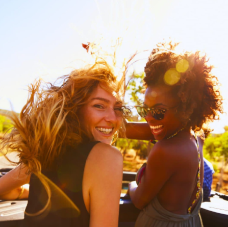Two women smiling and enjoying the sun outdoors.