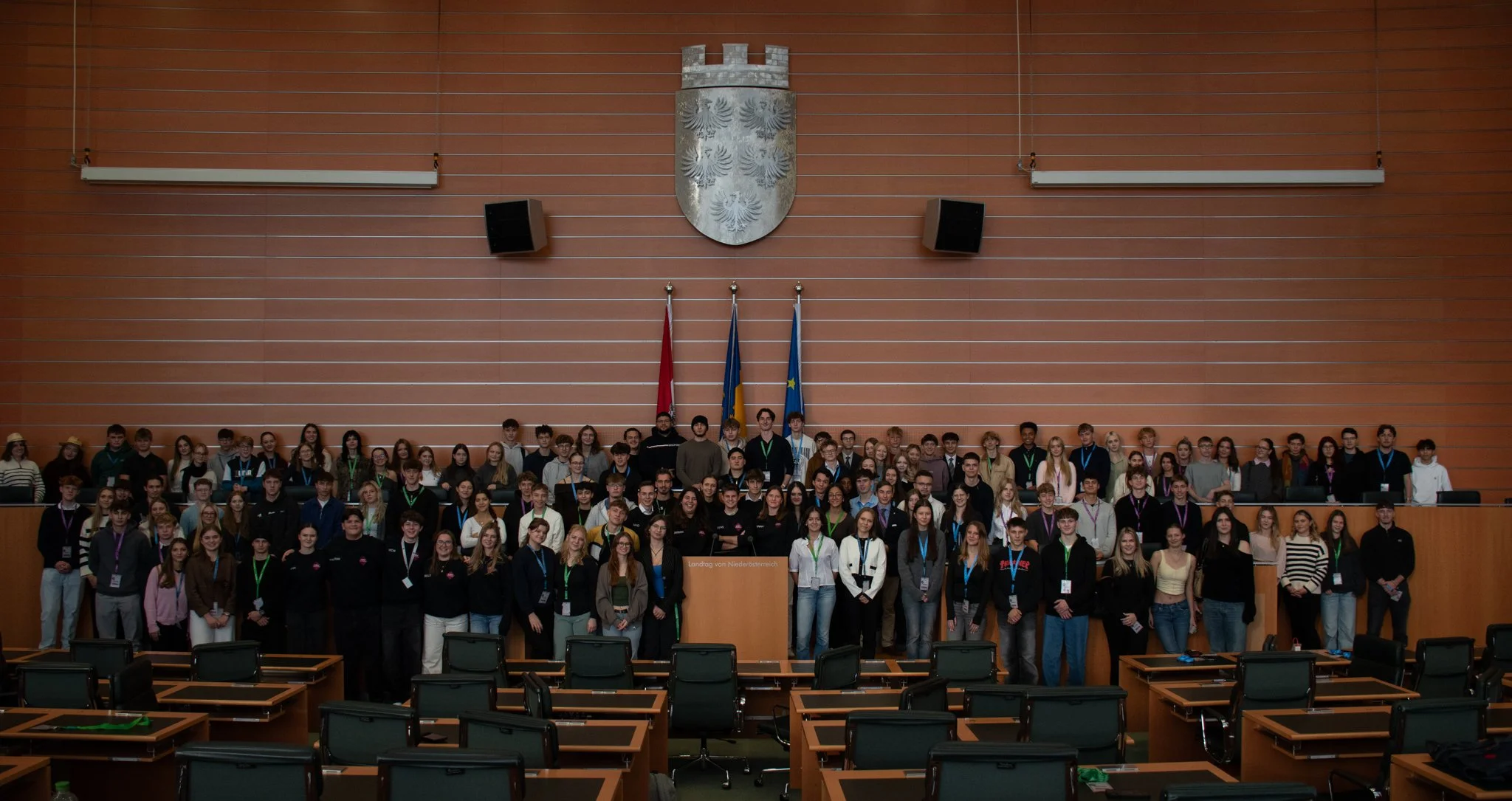 Gruppenfoto von vielen Jugendlichen und Erwachsenen in einem großen Saal mit Holzvertäfelung, Deutschlandfahnen, einem Wappen und einem Rednerpult.