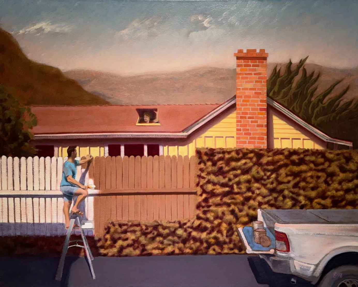 A person in blue shirt and shorts climbing a ladder to paint a wooden fence in a suburban yard. A woman peeks out of a window of a house with a brick chimney, and a truck with a bed full of fallen leaves is parked nearby. There are mountains and trees in the background.