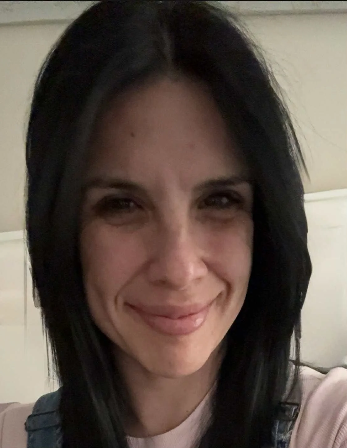 A woman with shoulder-length black hair smiling at the camera, wearing a light-colored top.