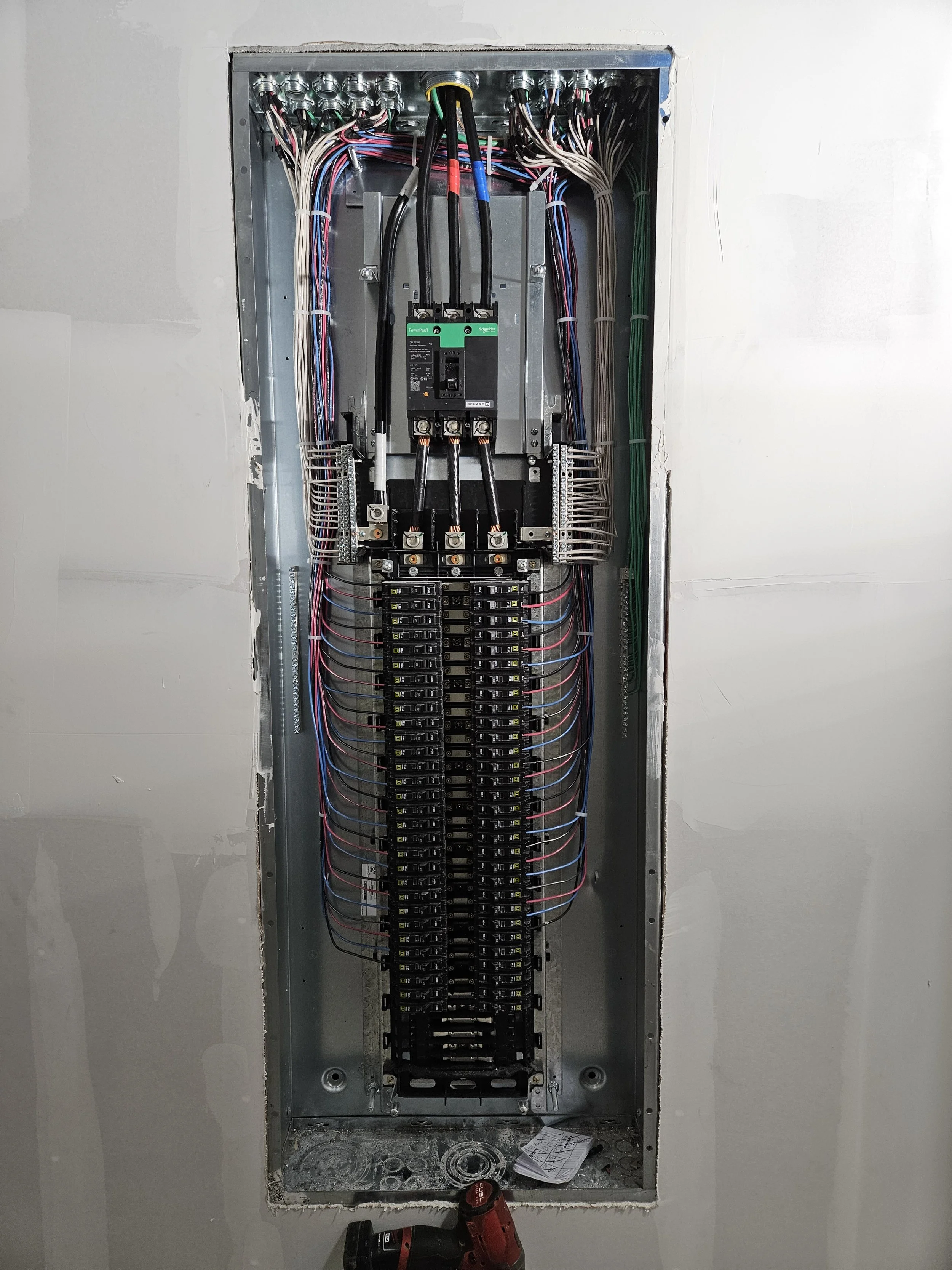 Electrical panel filled with wires, breakers, and a large circuit breaker in the center.