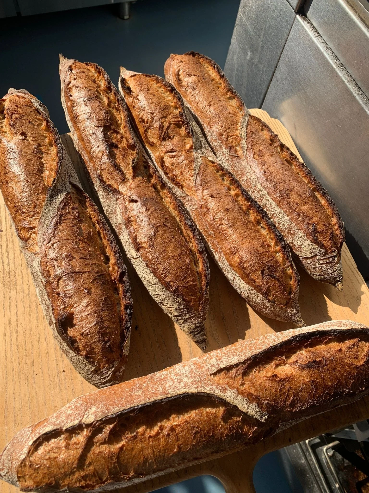 Several freshly baked baguettes on a wooden cutting board.