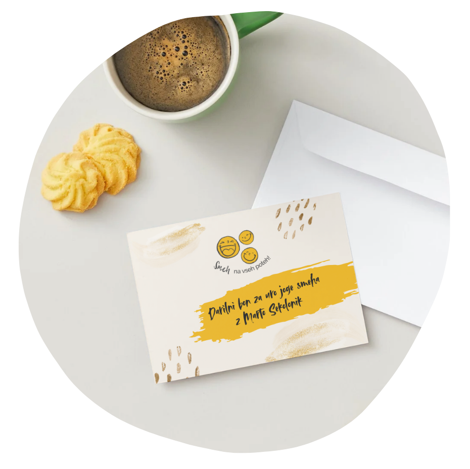 A white table with a green coffee mug filled with coffee, a couple of cookies, a white envelope, and a greeting card with smiley faces and text in Slovenian.