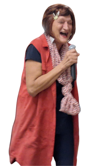 A woman with short brown hair wearing a hair clip, a red vest, a black shirt, and a striped scarf, holding a microphone and laughing.