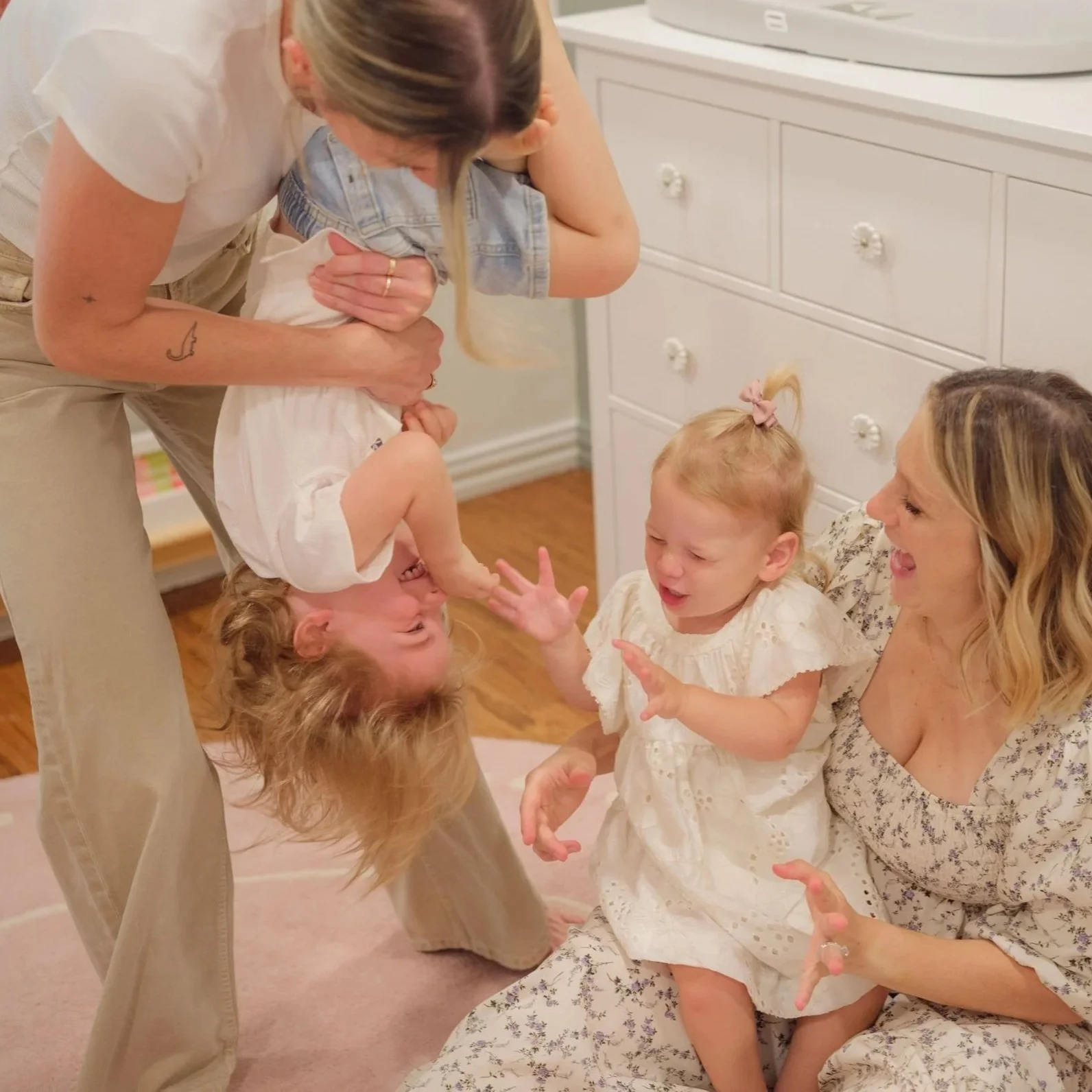 We Like to Potty founders Meagan Wentz and Hailey Blake playing with children on the floor in a room with a white dresser.