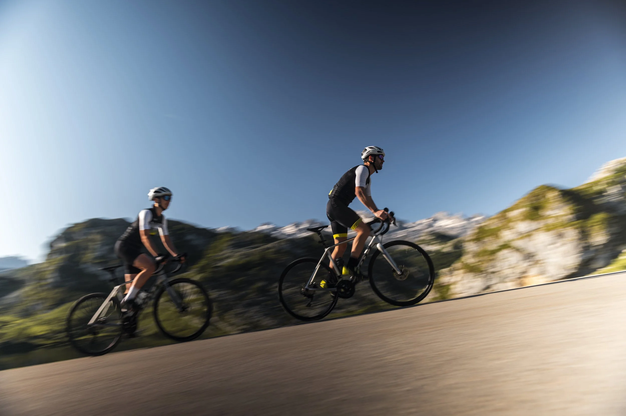 Ciclistas entrenando en carretera de montaña, acción difuminada