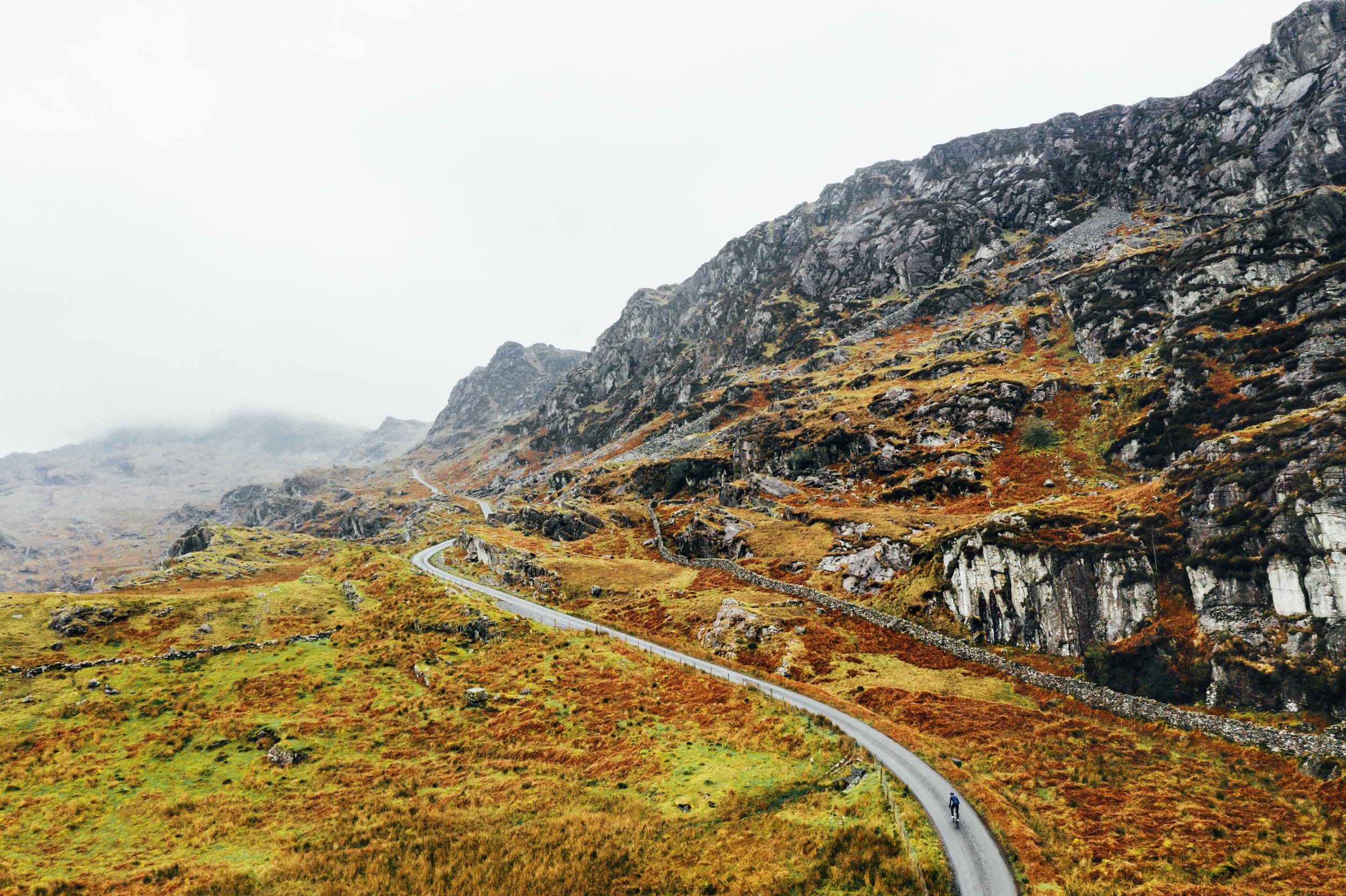 Ciclista de estrada se exercita em condições climáticas adversas em uma estrada na montanha enevoada