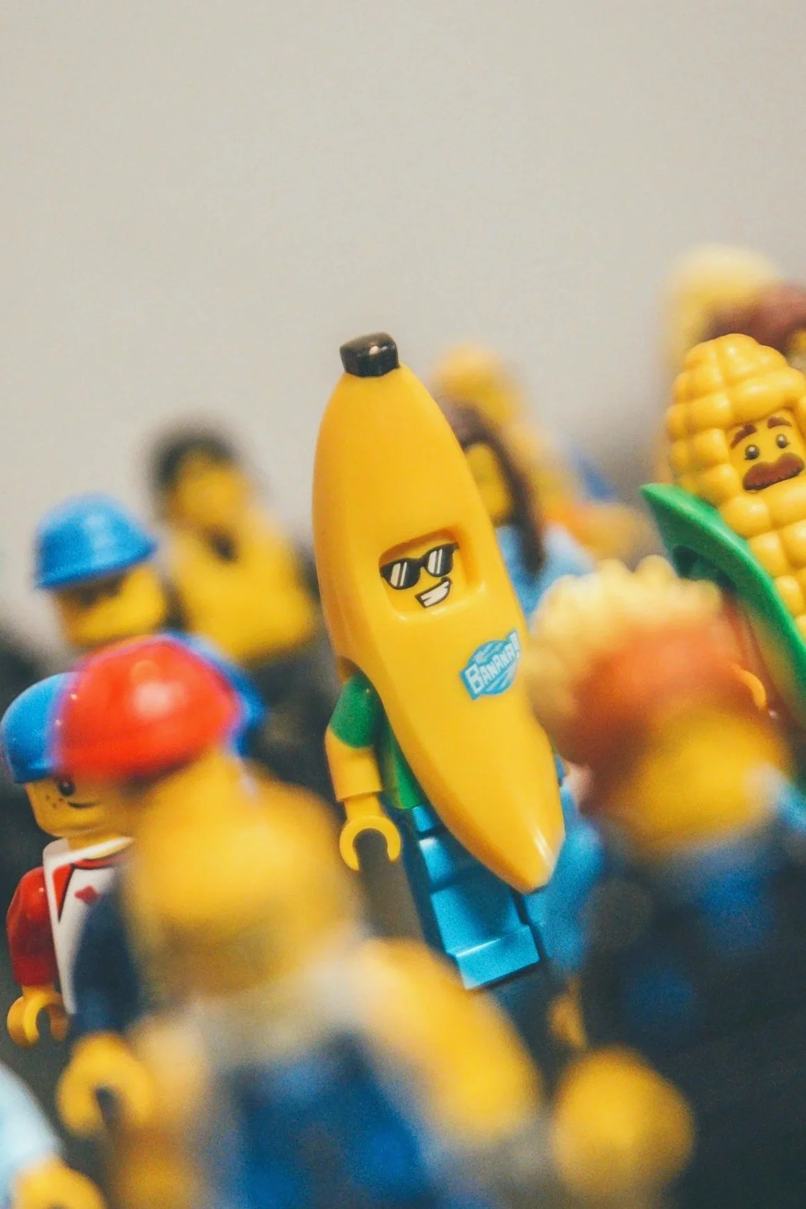 Lego-Figuren, darunter eine mit einer Bananenfigur, die Sonnenbrille trägt, vor einer weißen Wand.