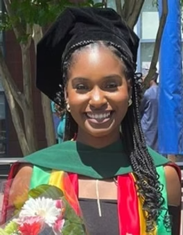 Smiling woman in graduation gown holding a bouquet of flowers.