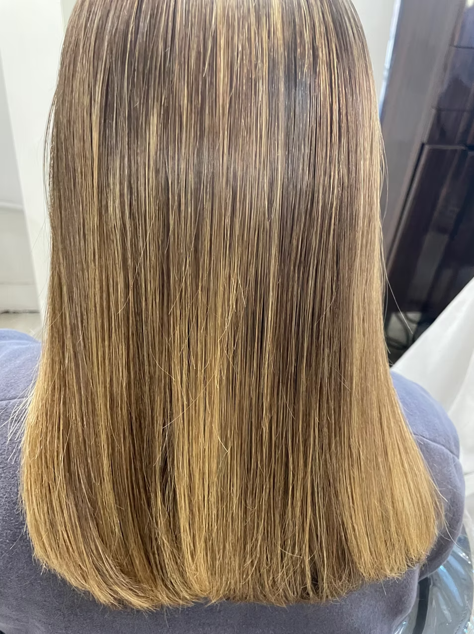 Back view of a person's head with long, straight, light brown hair.