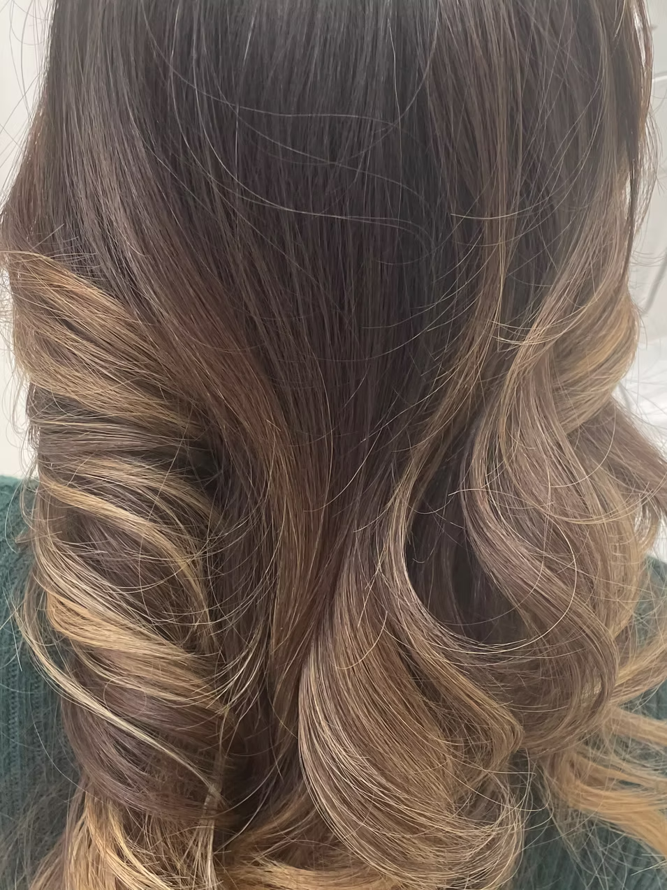 A close-up of long, wavy, brown hair with highlights.