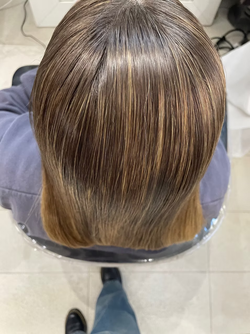 Top view of a person's head showcasing freshly styled, shiny, light brown hair with highlights.