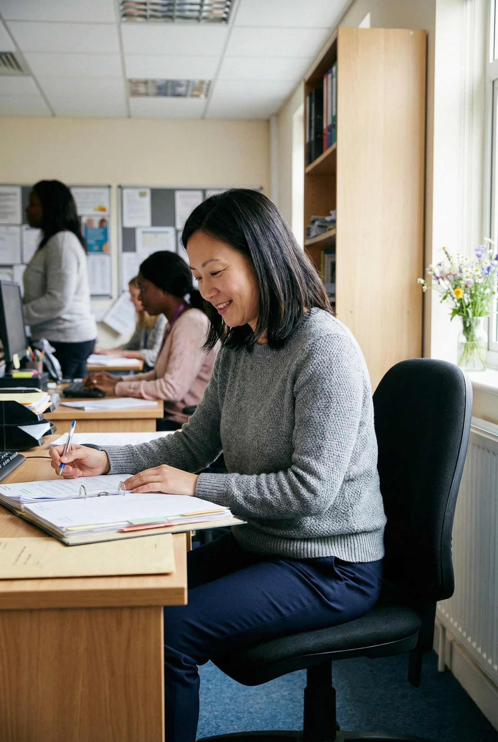 Social worker reviewing case notes at a desk in a UK social work office