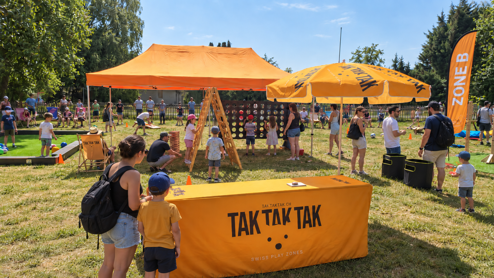 Children and adults participating in outdoor activities at a park with tents, umbrellas, and games, under a clear blue sky.
