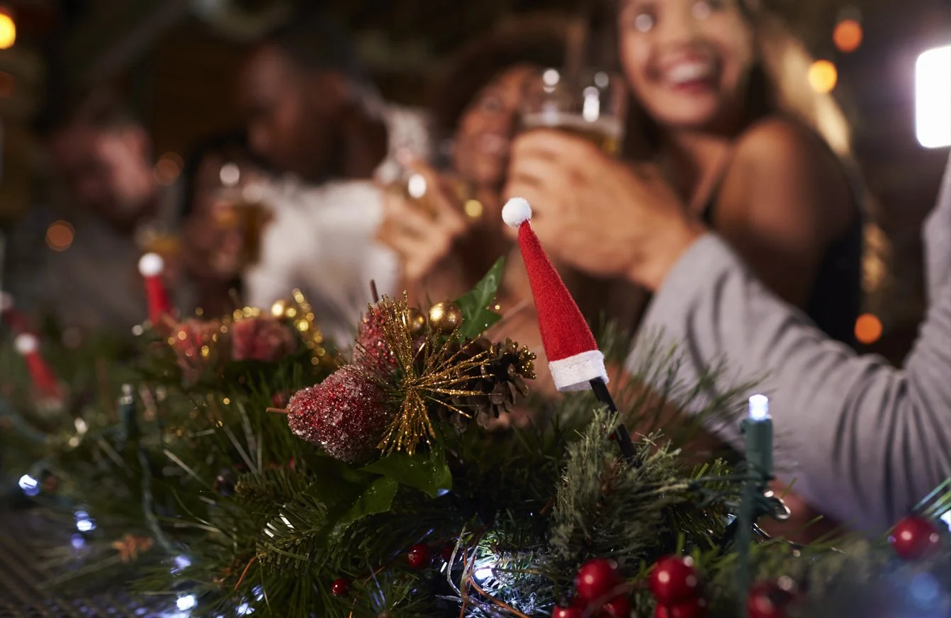 Groupe célébrant Noël autour d’une table décorée et levant leurs verres