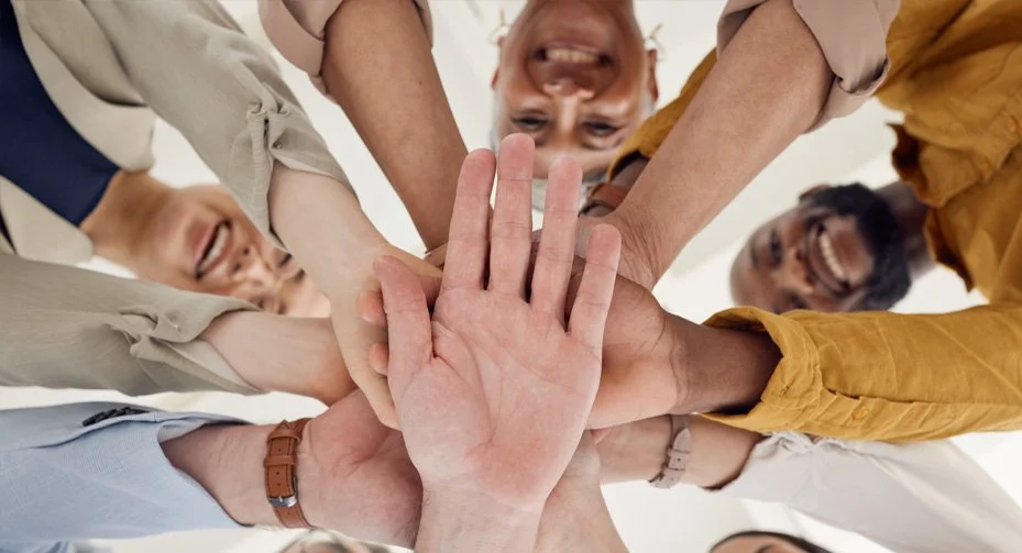 Groupe de participants souriants réunissant leurs mains lors d’un moment collectif