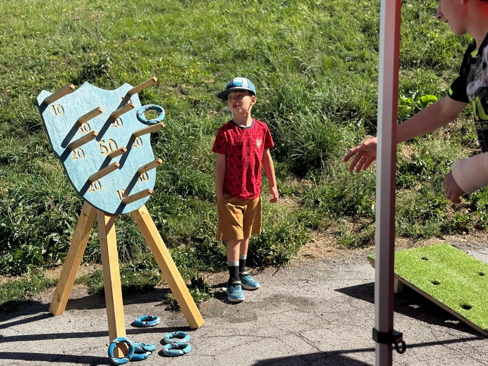Enfant jouant à un jeu d’anneaux en bois lors d’un événement en plein air