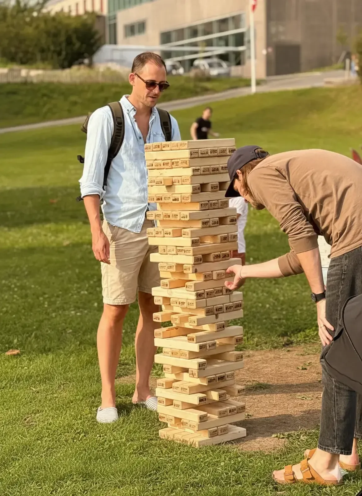 Deux hommes jouent au Jenga géant dans un parc pendant une journée de fête d'entreprise