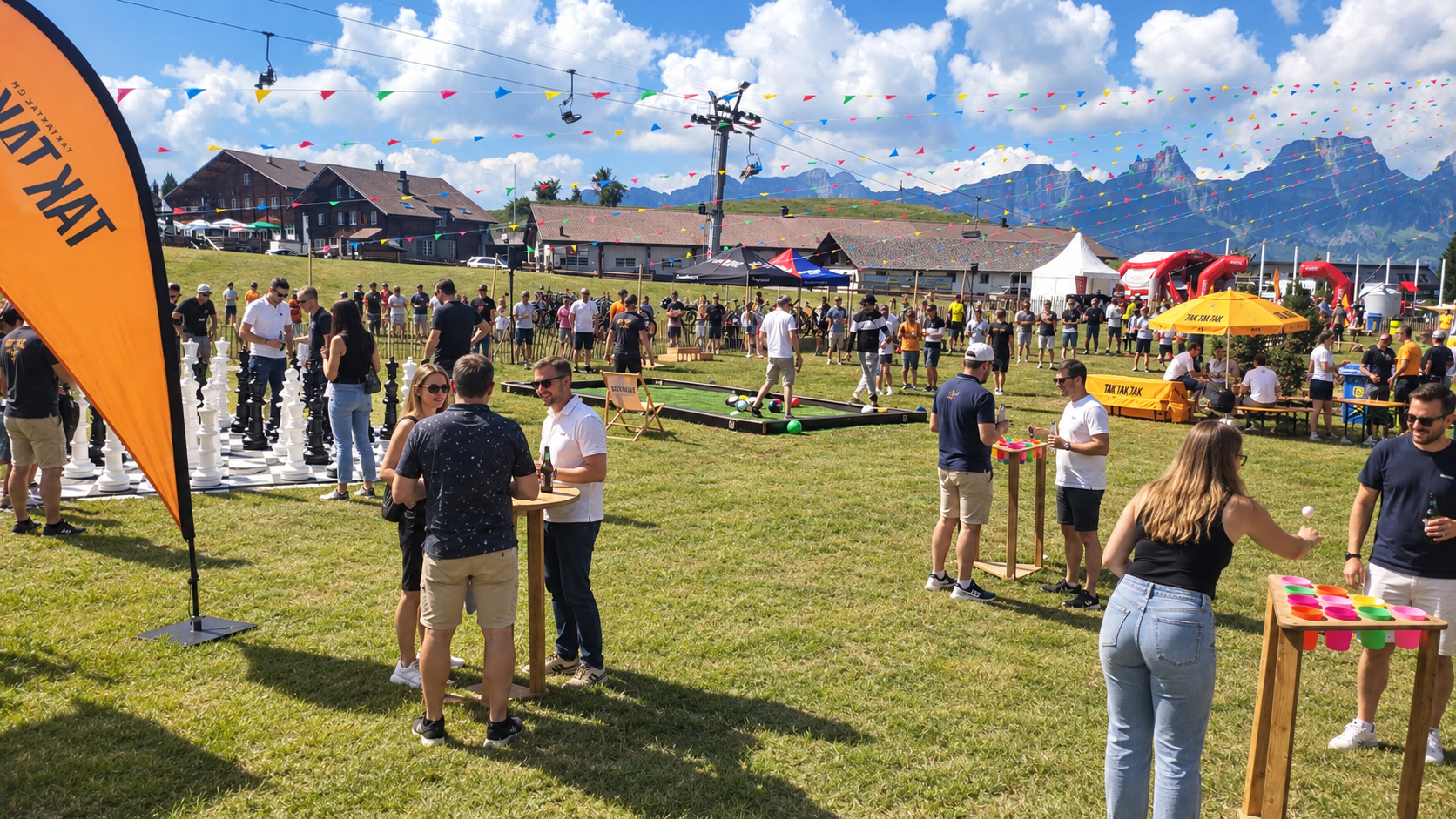 People enjoying outdoor festival with games, food tents, and mountain scenery in the background on a sunny day.
