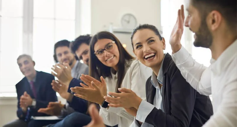 Groupe de collaborateurs souriant et applaudissant lors d’un événement d’entreprise