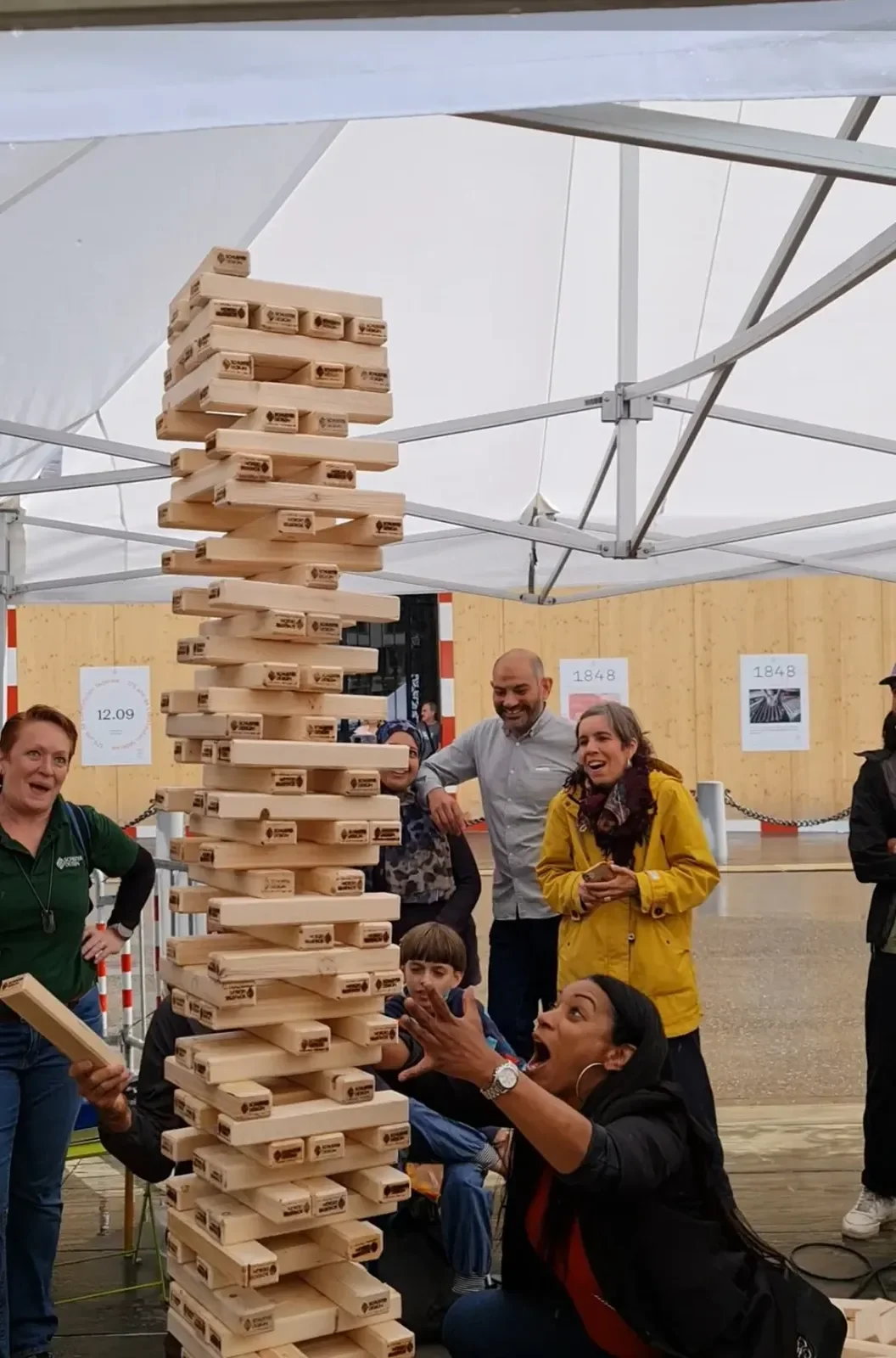 Participants jouent à un Jenga géant en bois lors d’une animation de jeux géants pendant un événement.