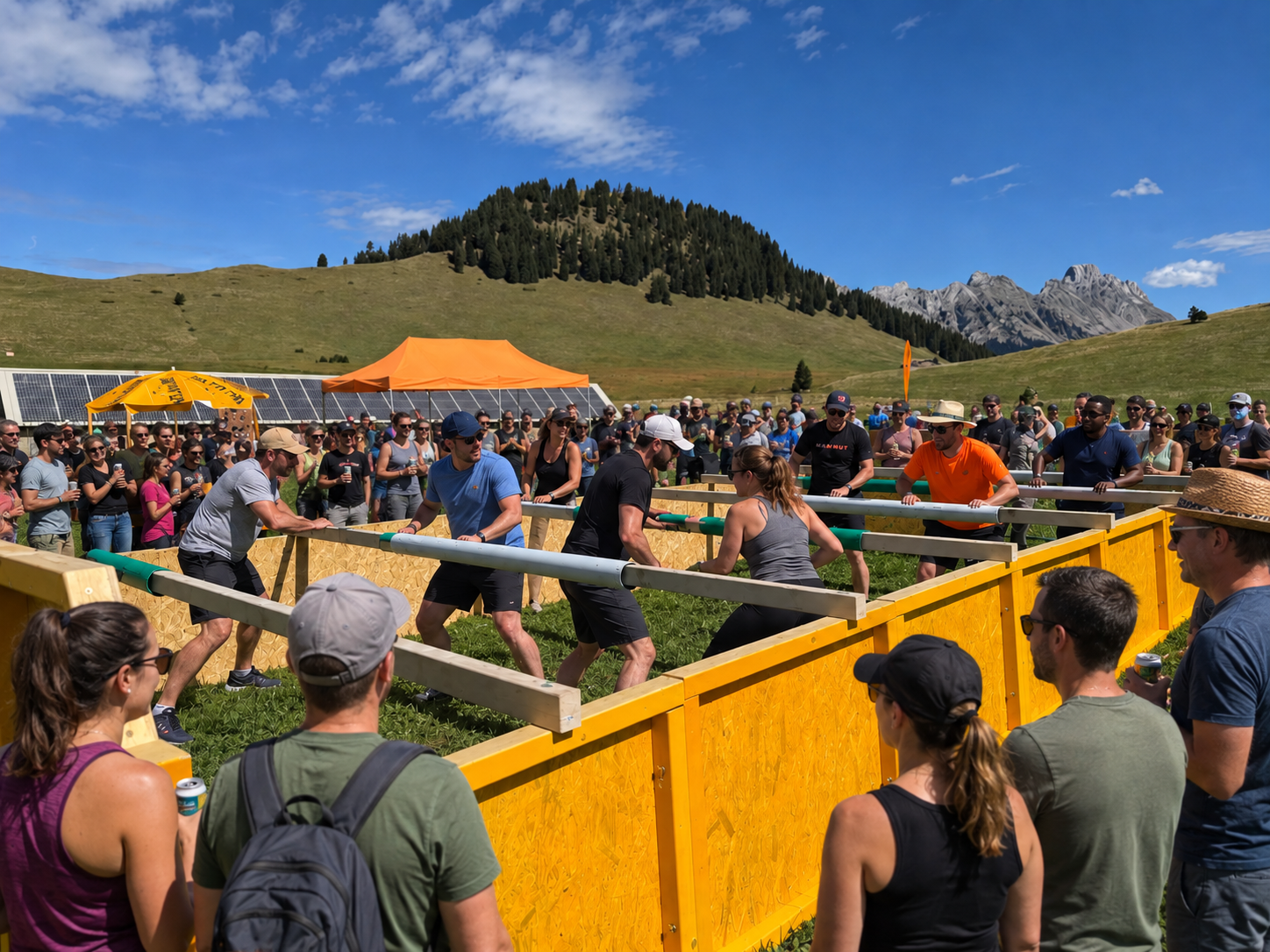 People playing a game in a fenced ring outdoors with mountains and hills in the background, and a crowd watching.