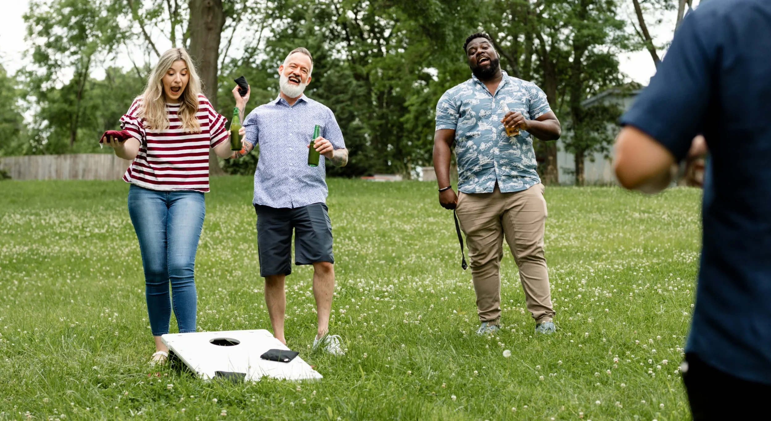 Groupe jouant au Cornhole et échangeant autour d’un verre en plein air