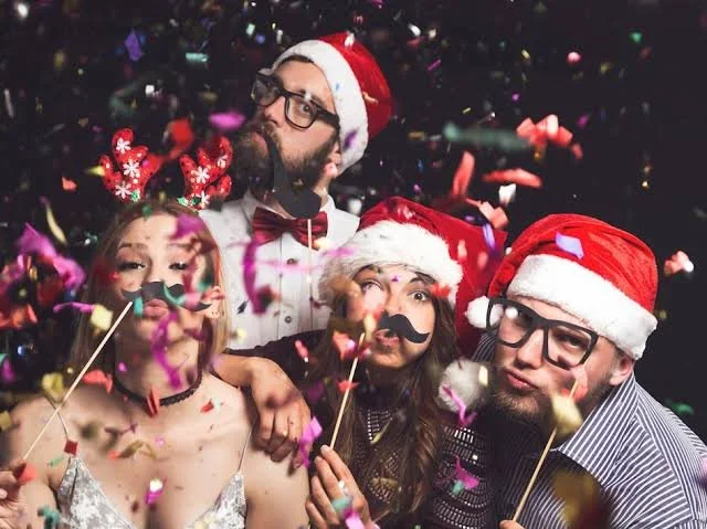 Groupe célébrant une fête de Noël avec bonnets de Père Noël et accessoires festifs
