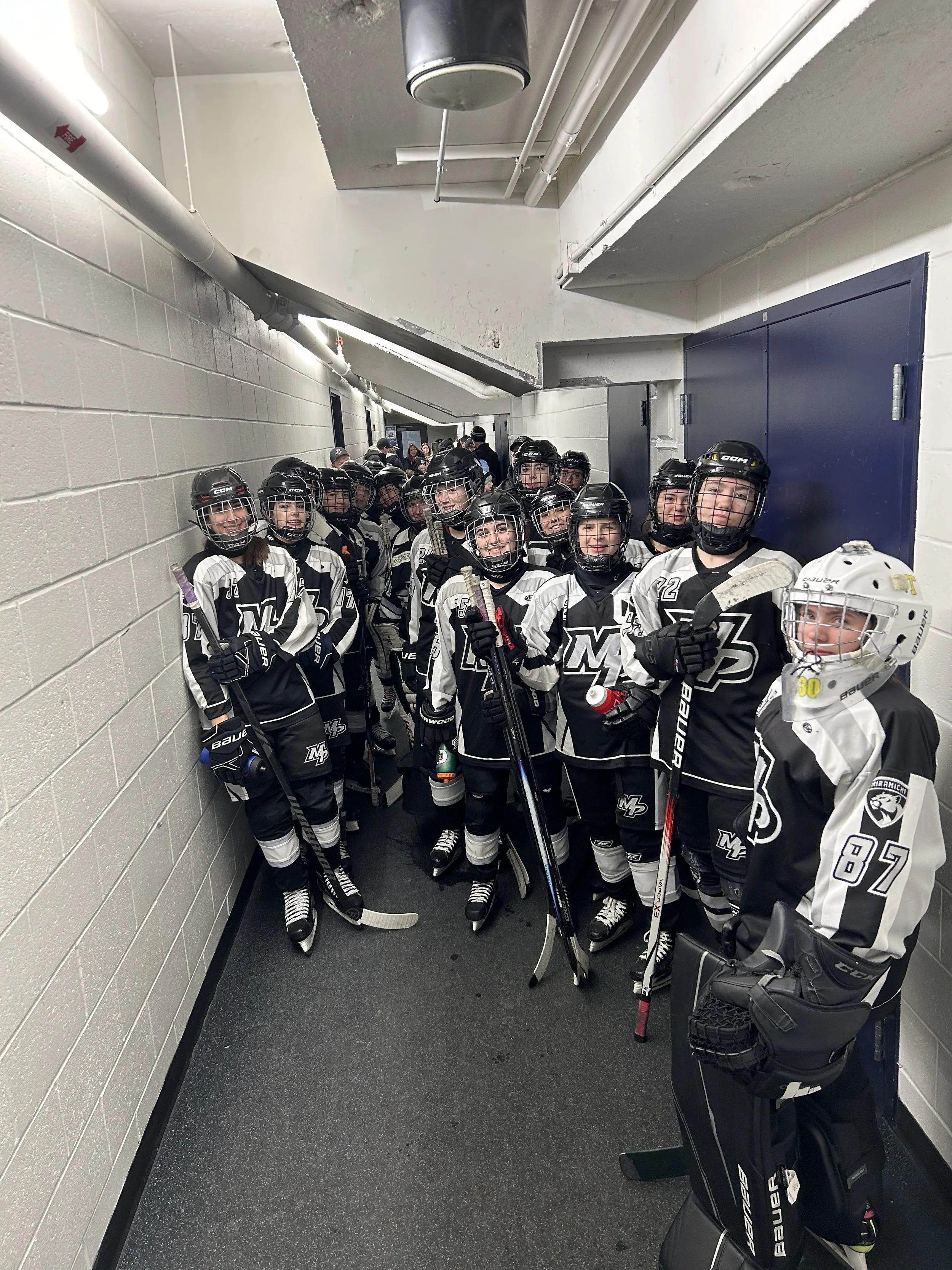 Hockey team in uniform and helmets standing in a hallway before a game.