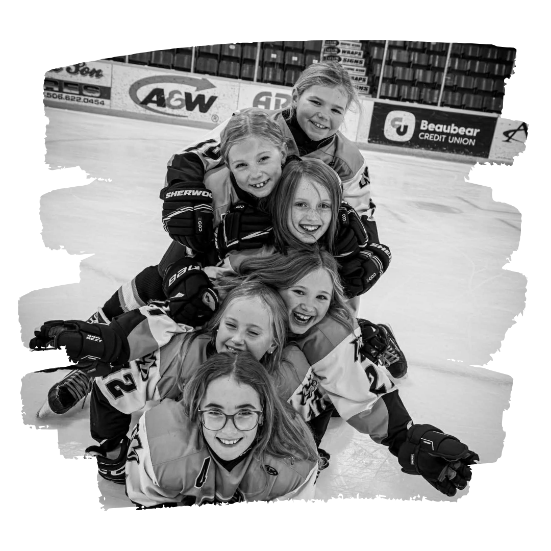 Group of girls in hockey gear stacked in a pyramid on the ice rink.