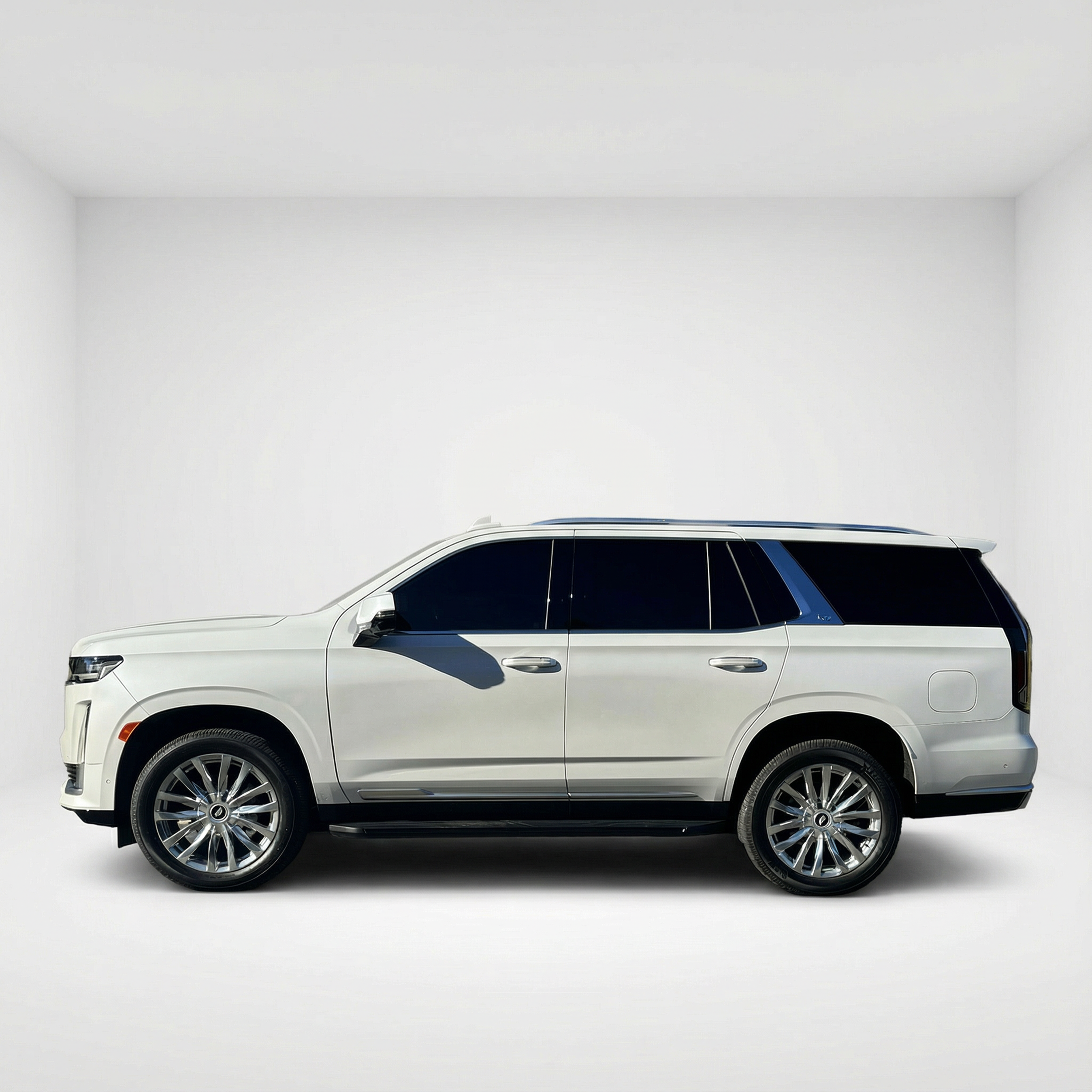 Side profile of a 2022 white Cadillac Escalade in an all-white studio setting