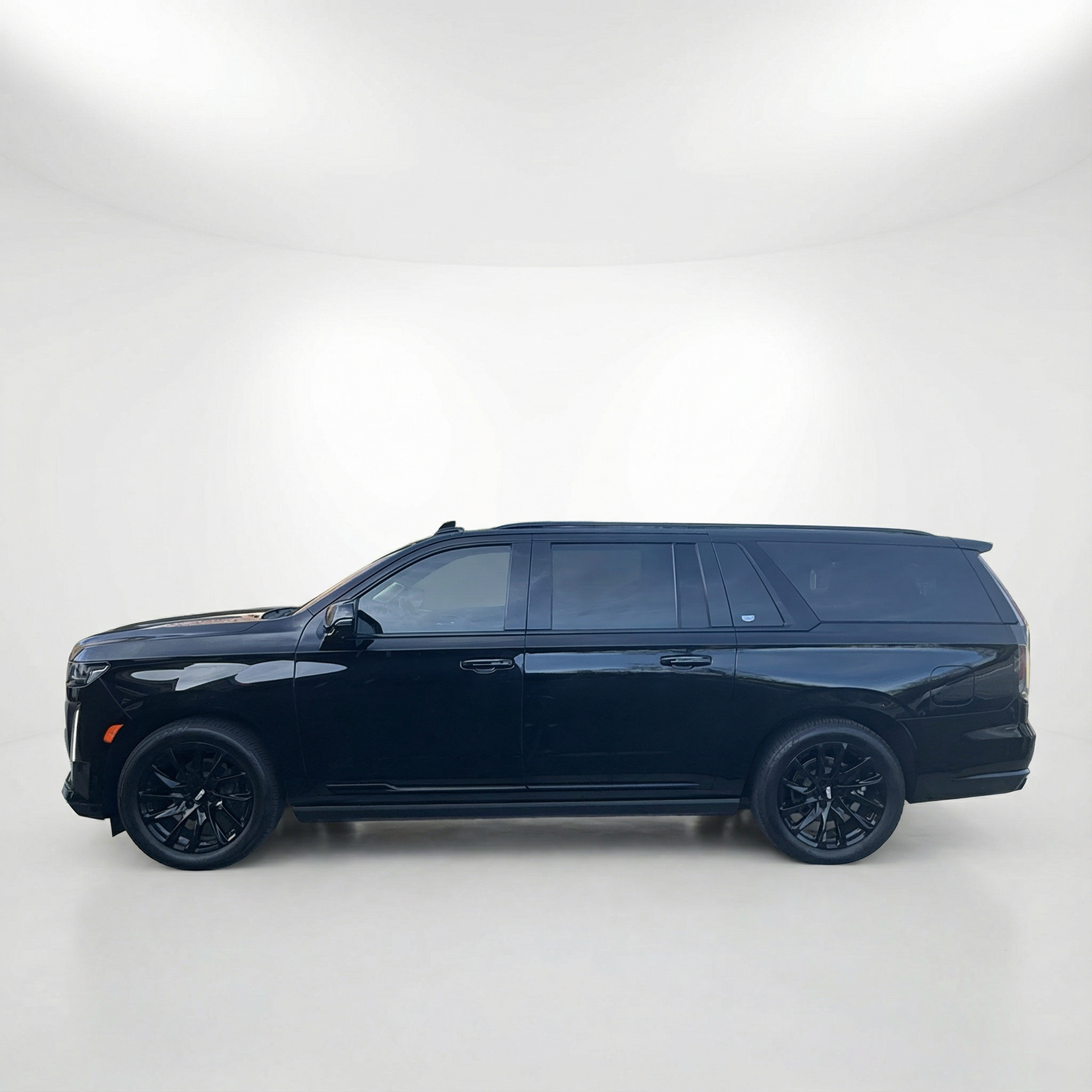 Side profile of a 2021 black Cadillac Escalade in an all-white studio setting