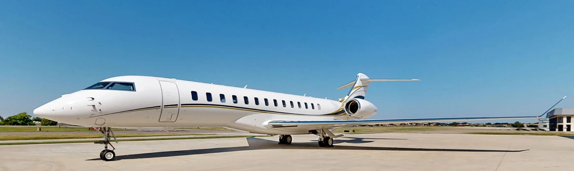 A white private jet airplane parked on an airport tarmac under a clear blue sky.