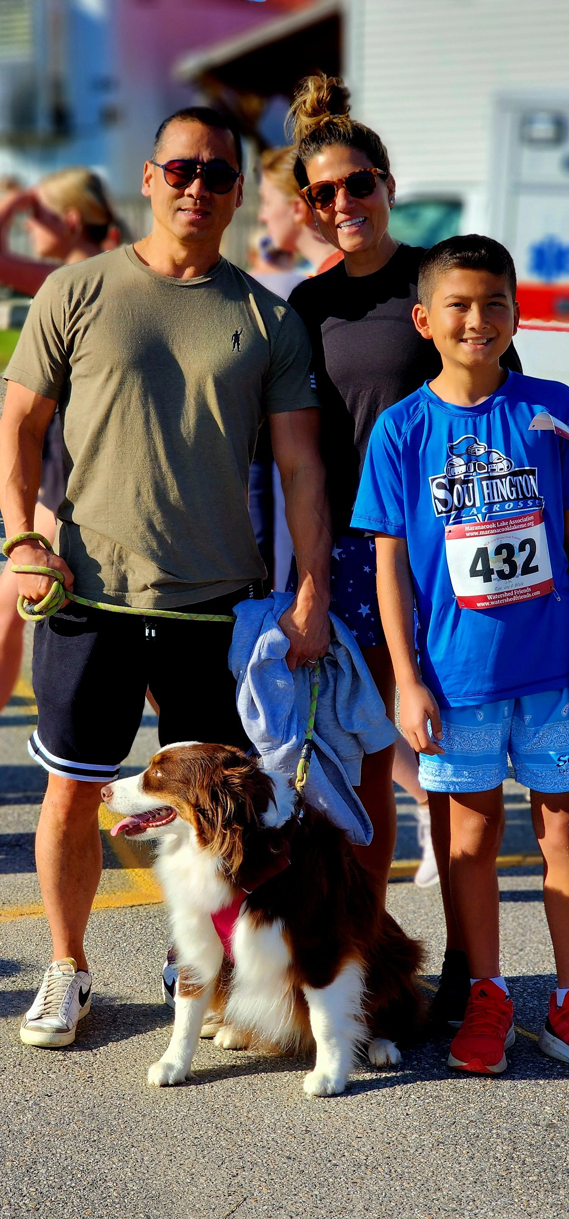Three people and a dog smiling at the camera