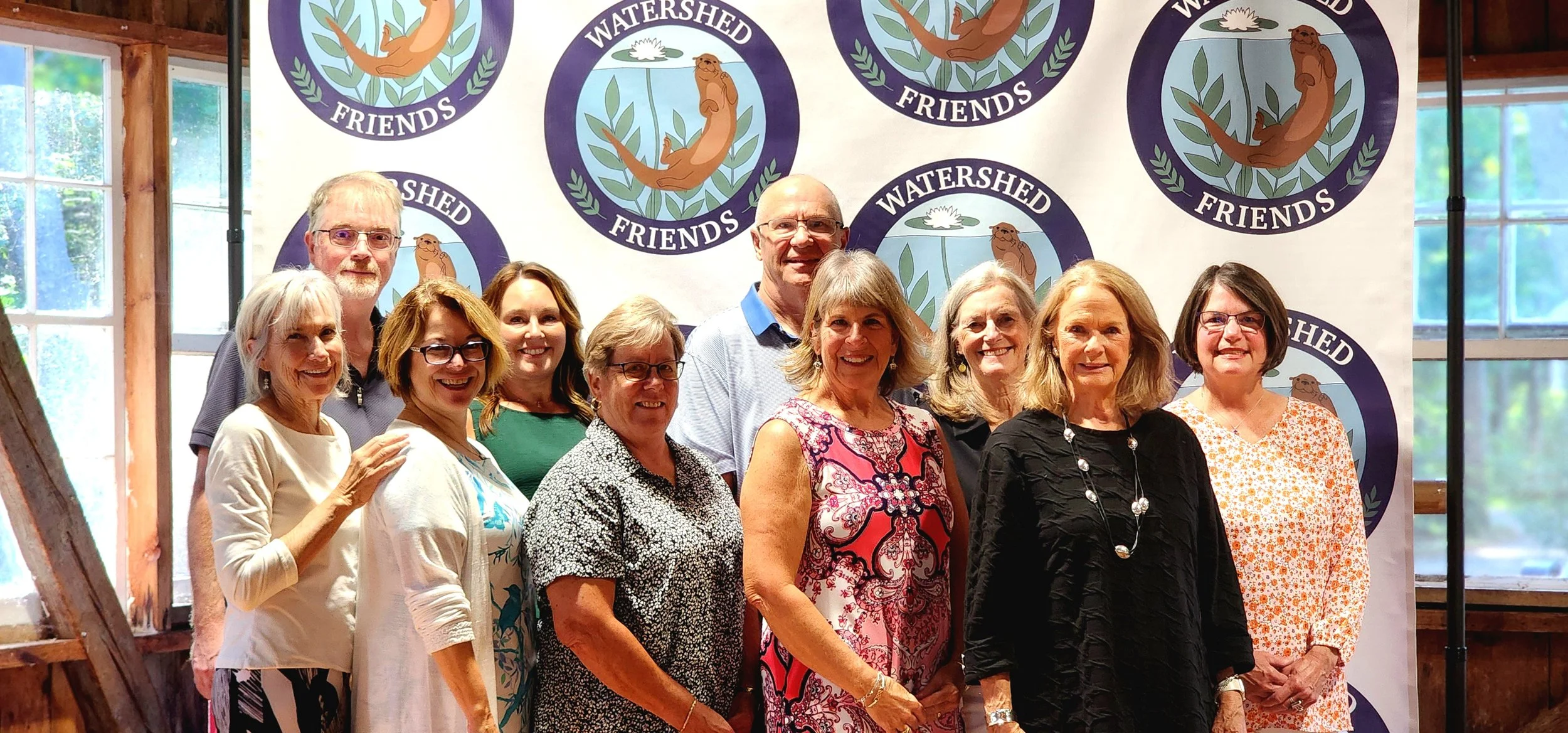Ten people standing in front of a backdrop with the Watershed Friends logo