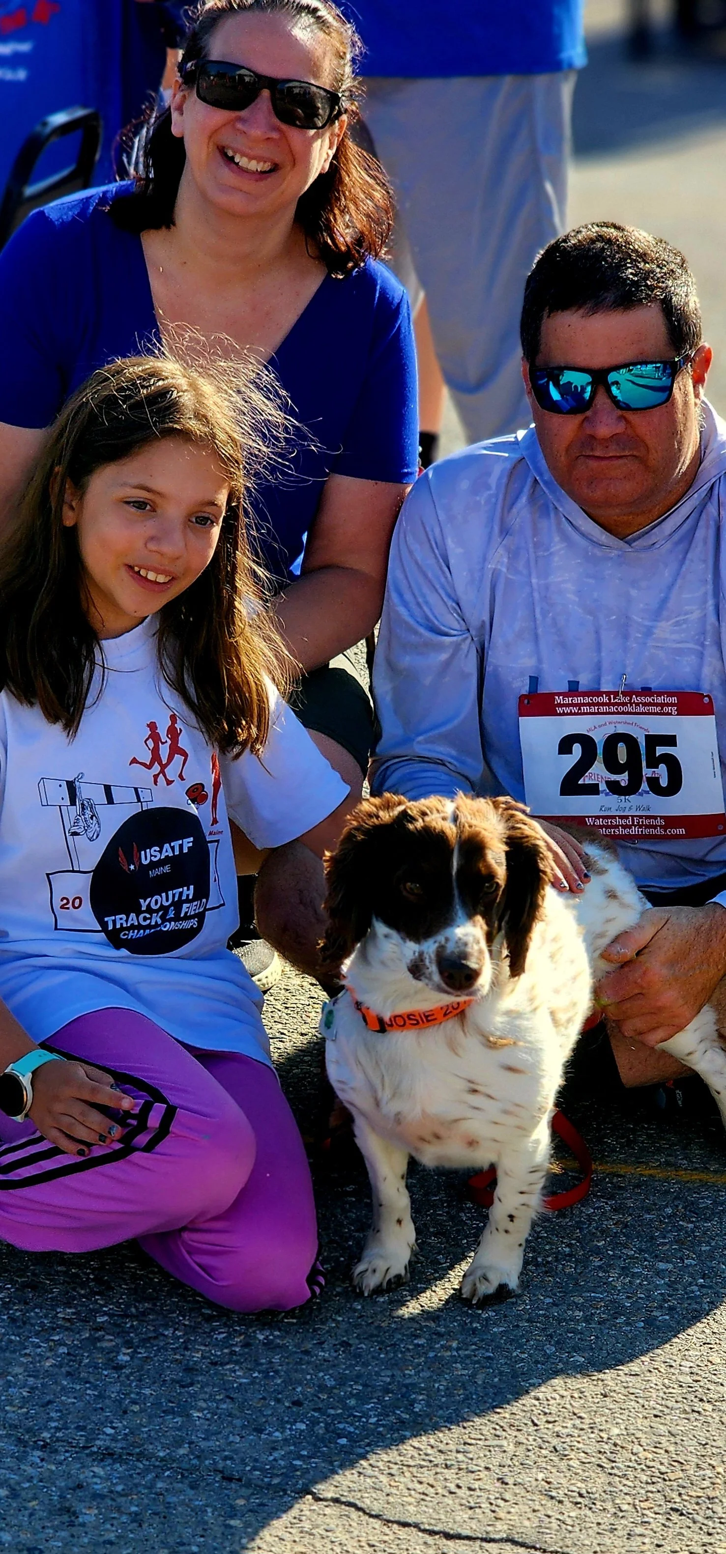 Three people and a dog smiling at the camera