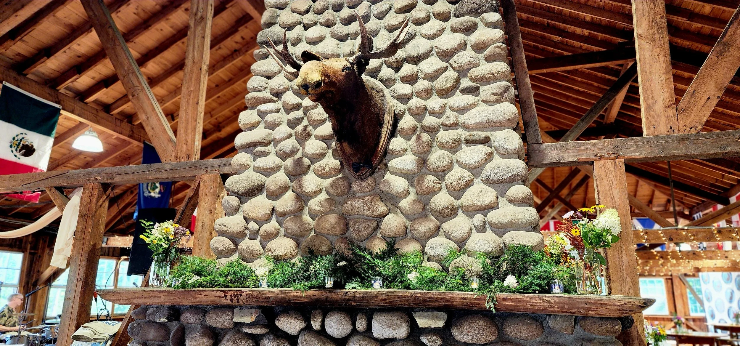 A fireplace with a mounted moose head and greenery arranged on the mantle