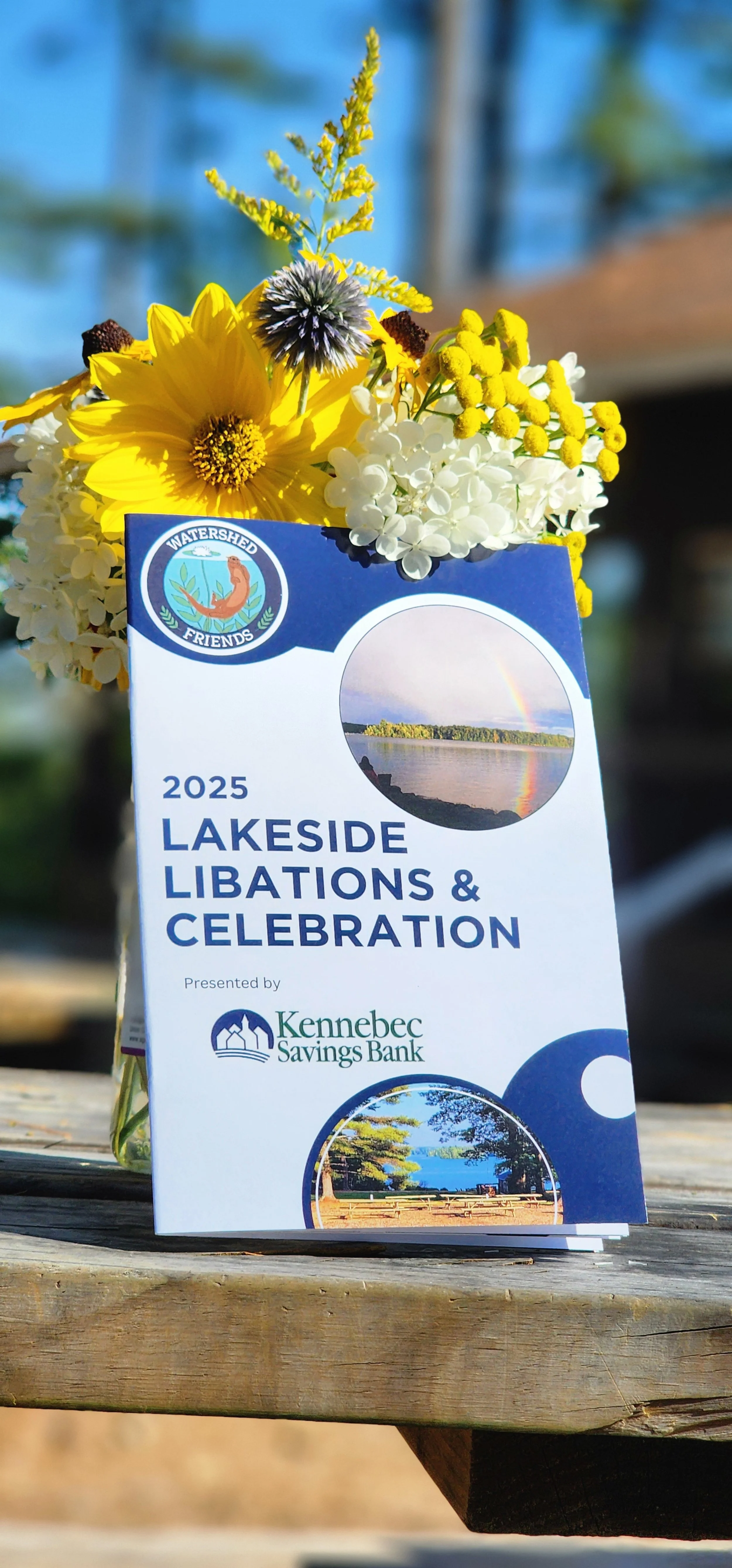 The 2025 Lakeside Libations & Celebrations program in front of a bouquet of flowers