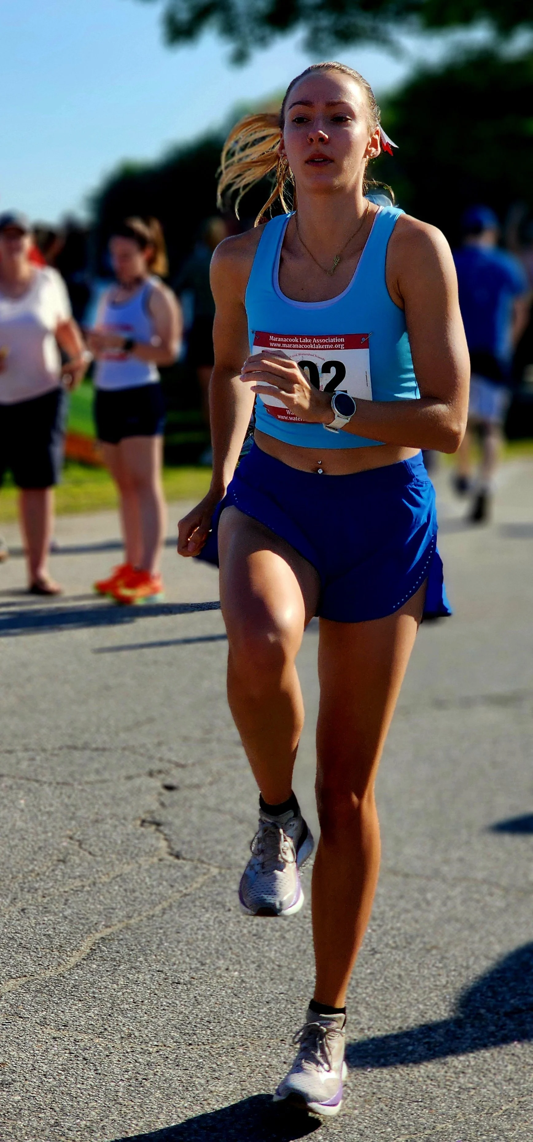 A woman, wearing a light blue tank top and blue shorts, skipping