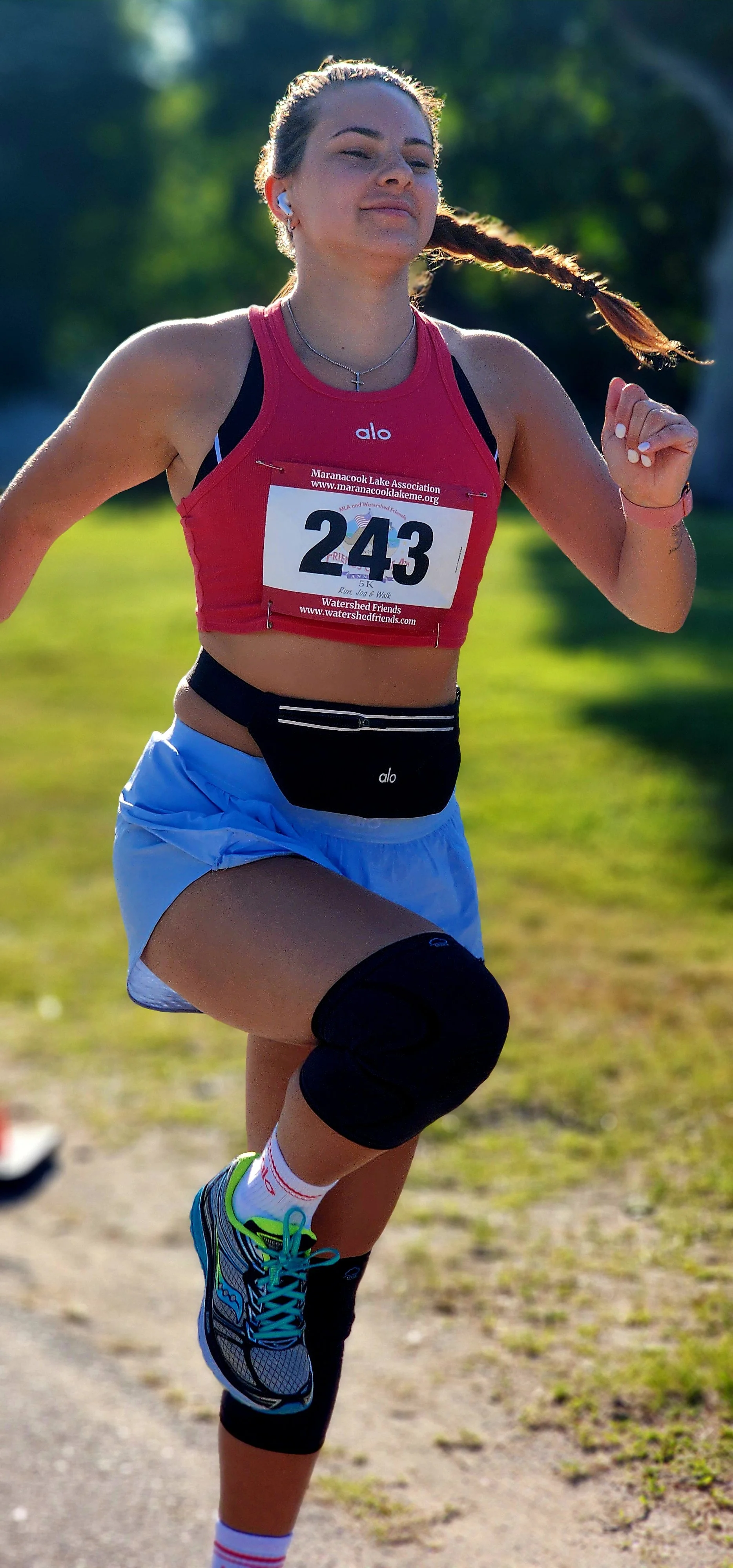 A woman, wearing a cropped red tank top and blue shorts, skipping