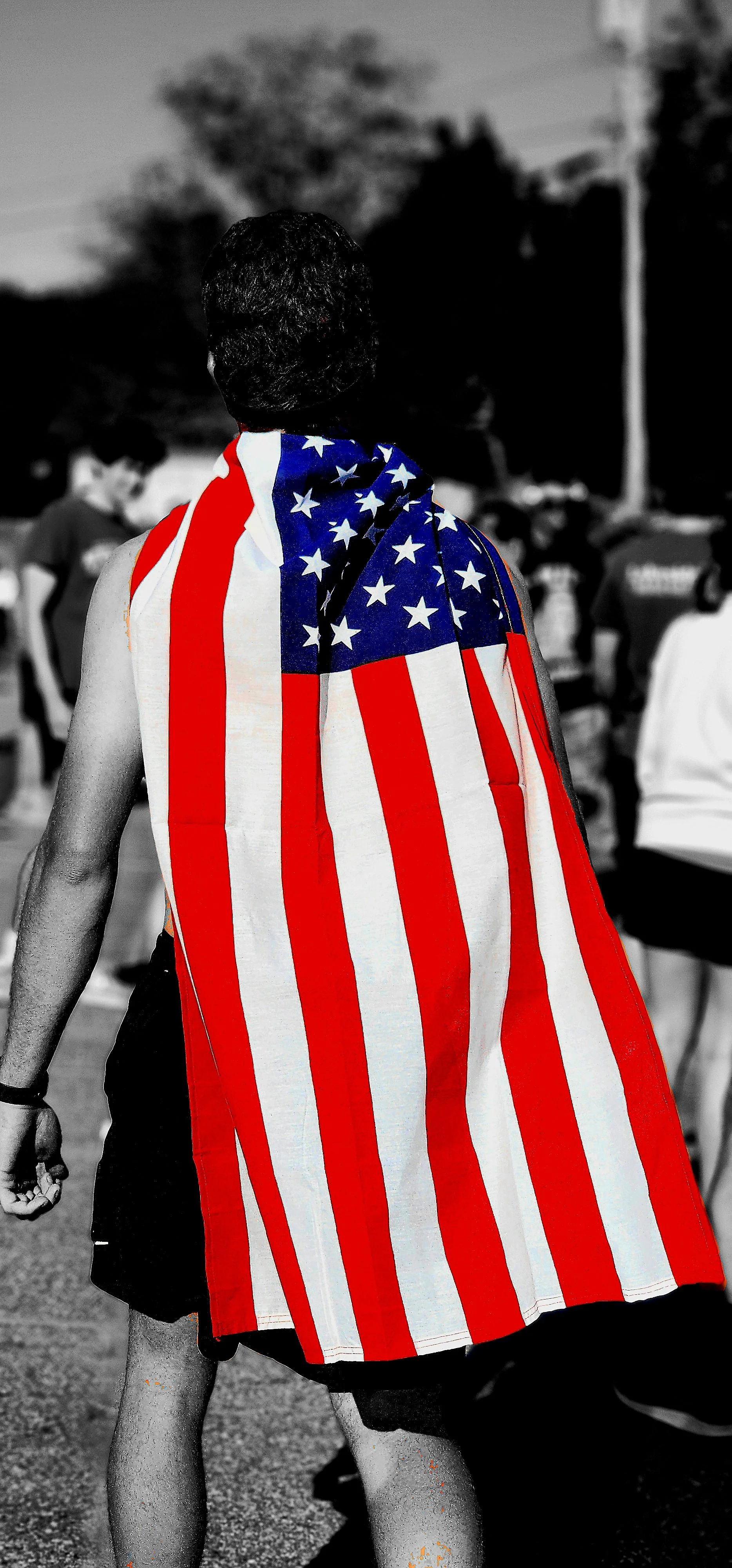 A back view of a man wearing the American flag as a cape
