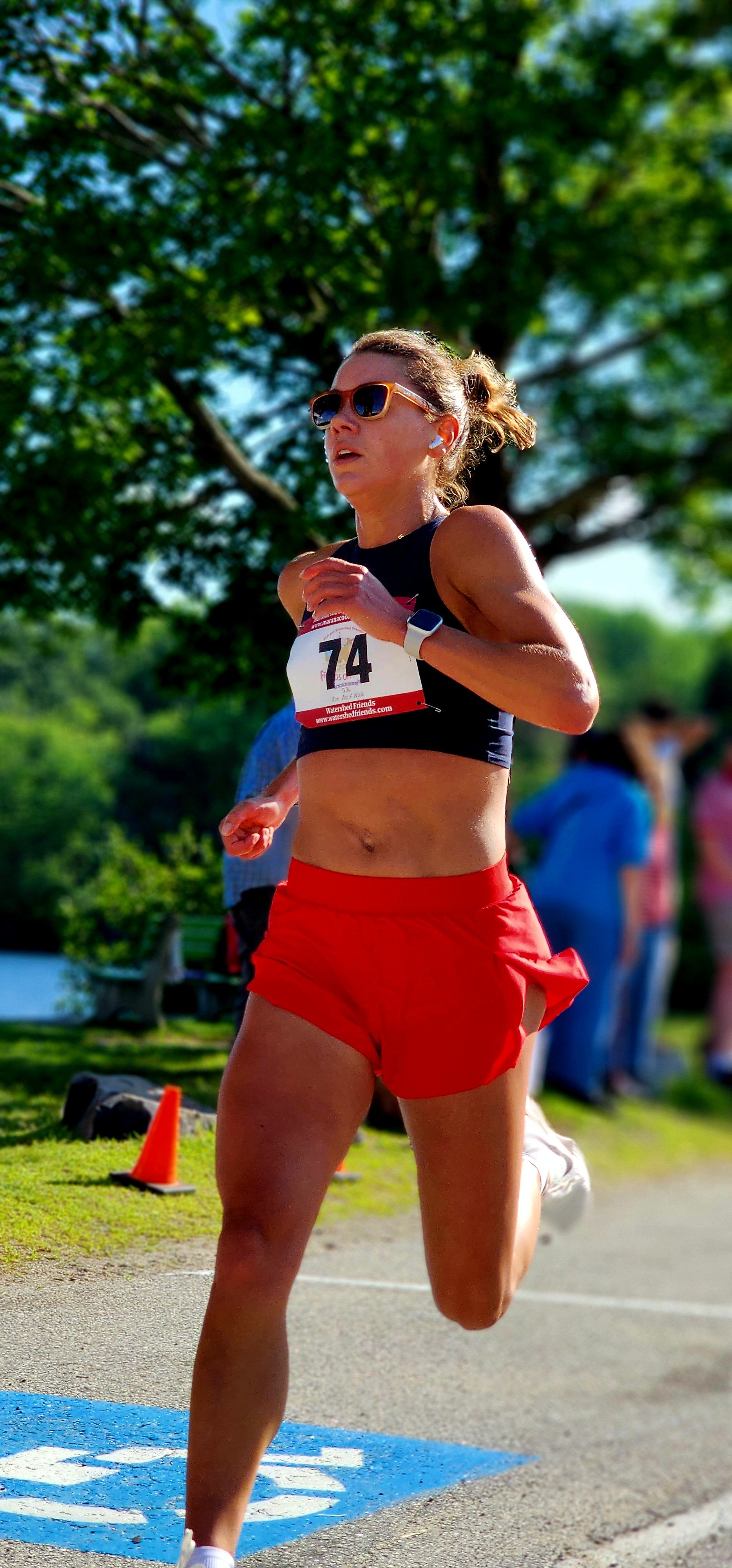A woman wearing a black sports bra and red shorts running
