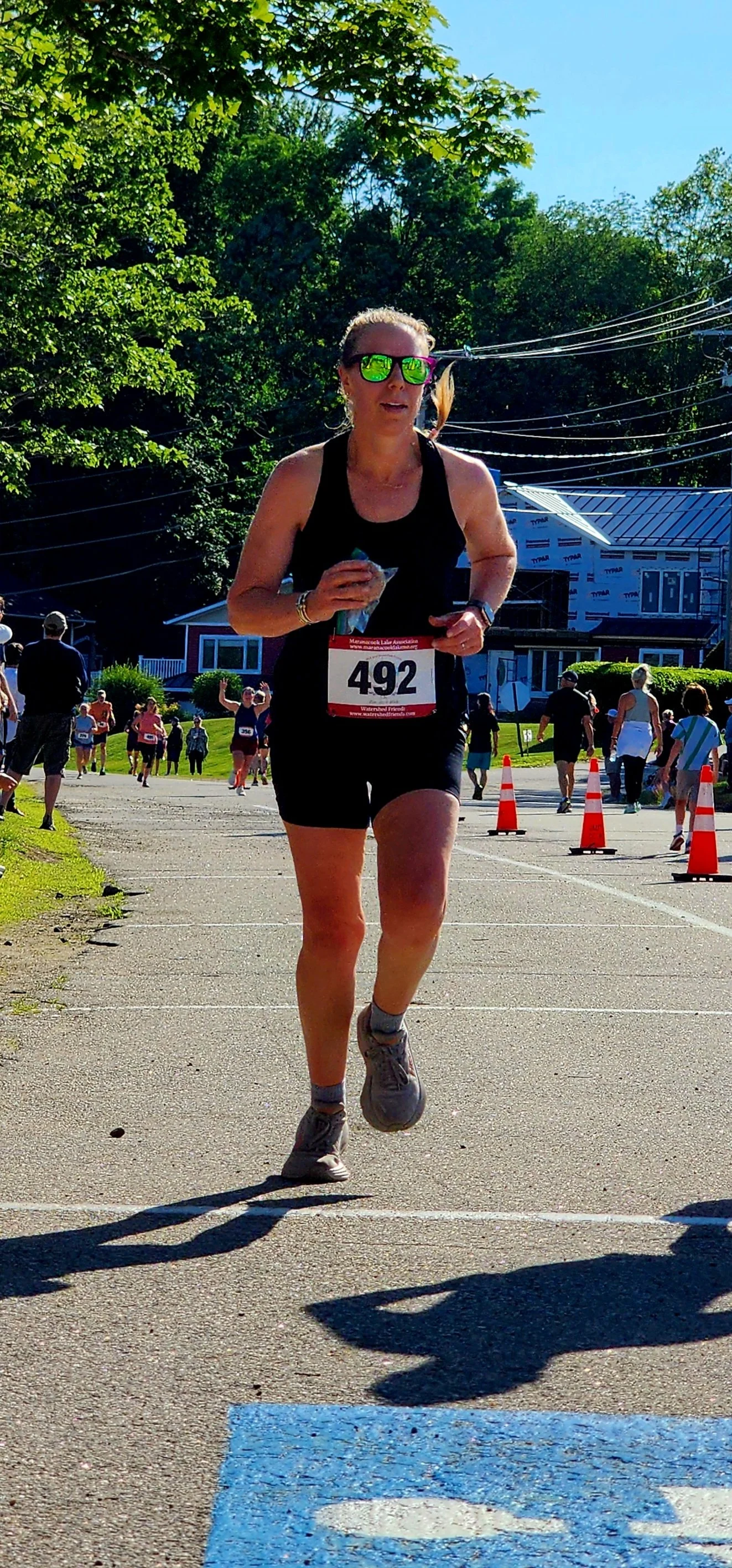A woman wearing a black tank top and shorts running