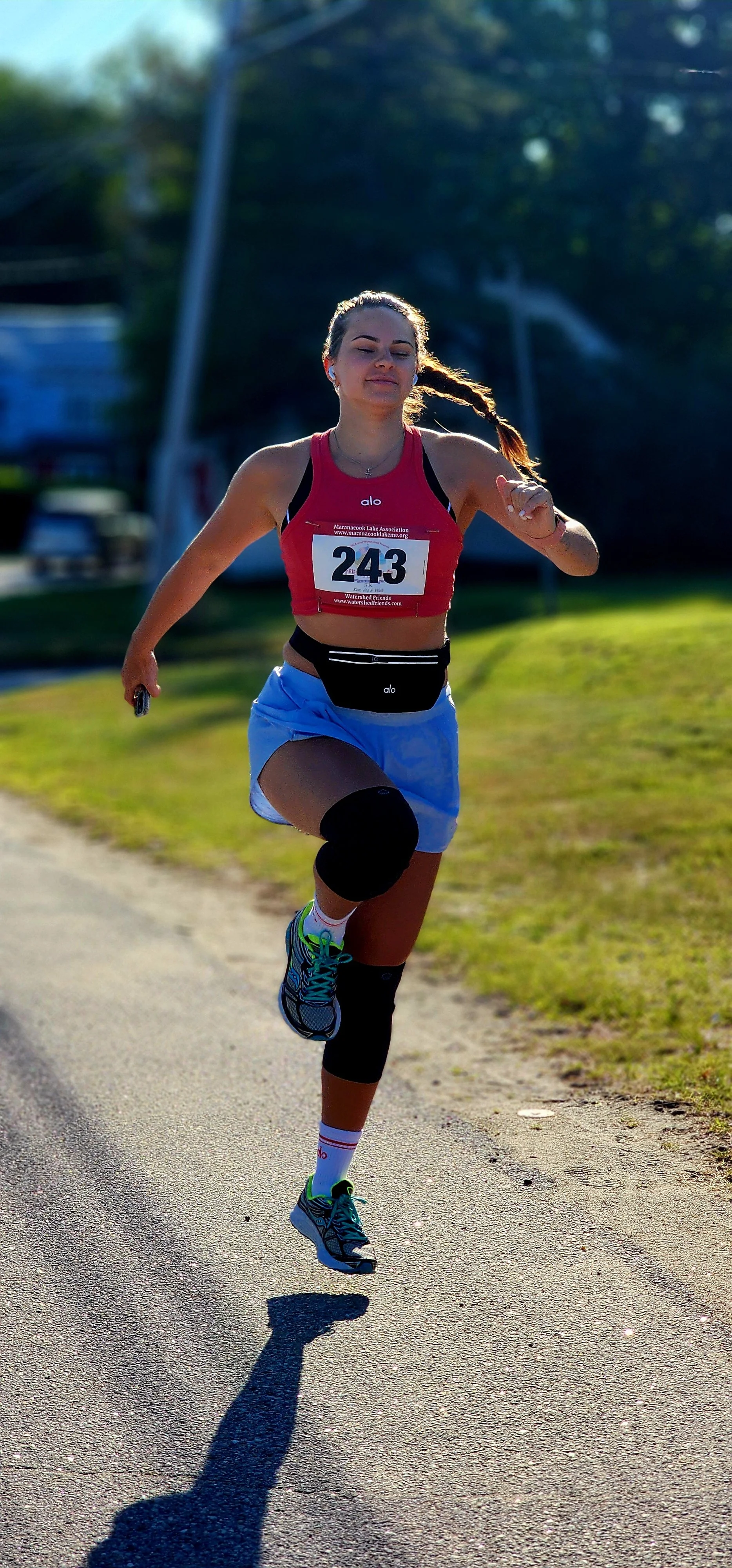 A woman wearing a red cropped tank top and blue shorts, skipping