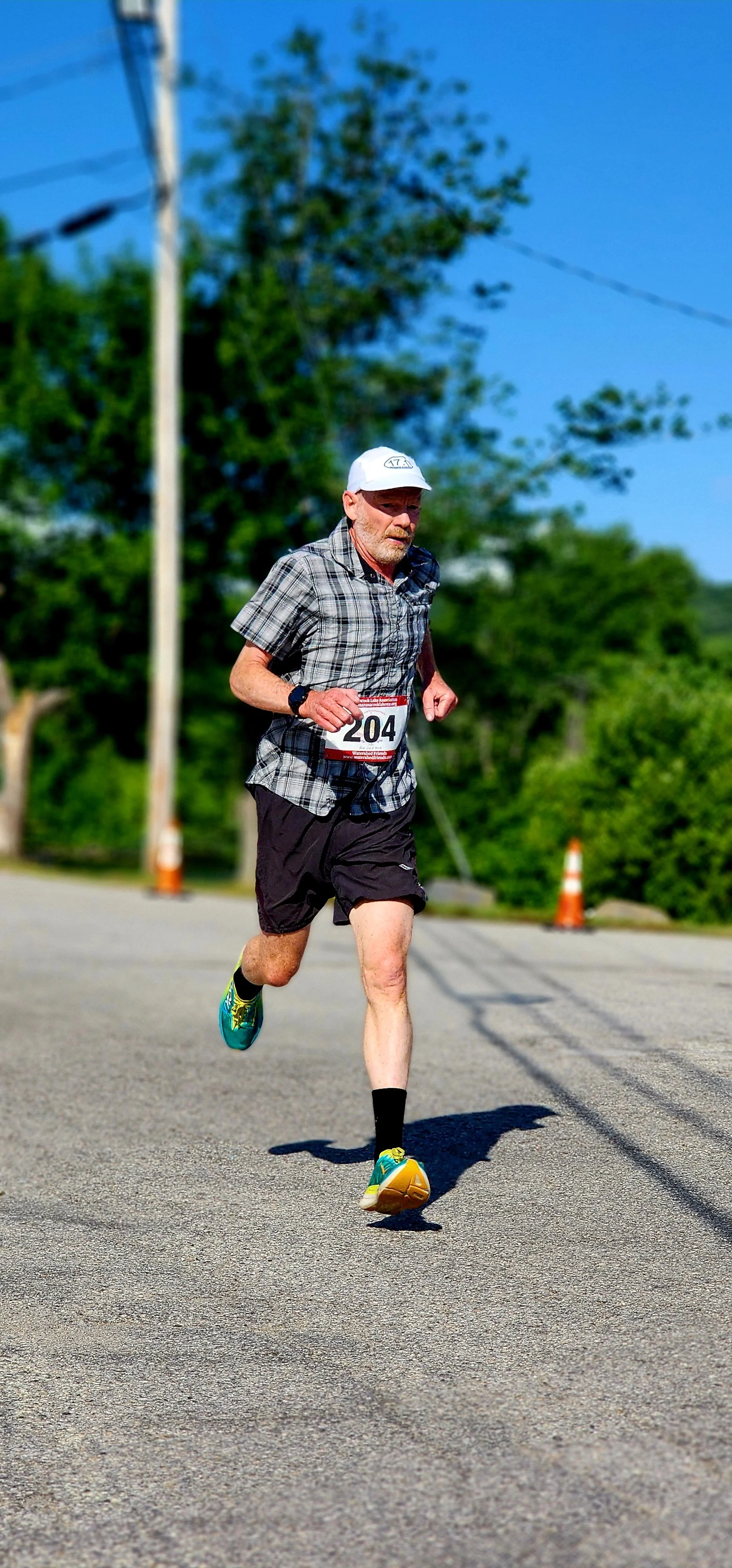 A man in a black and white plaid shirt and black shorts running