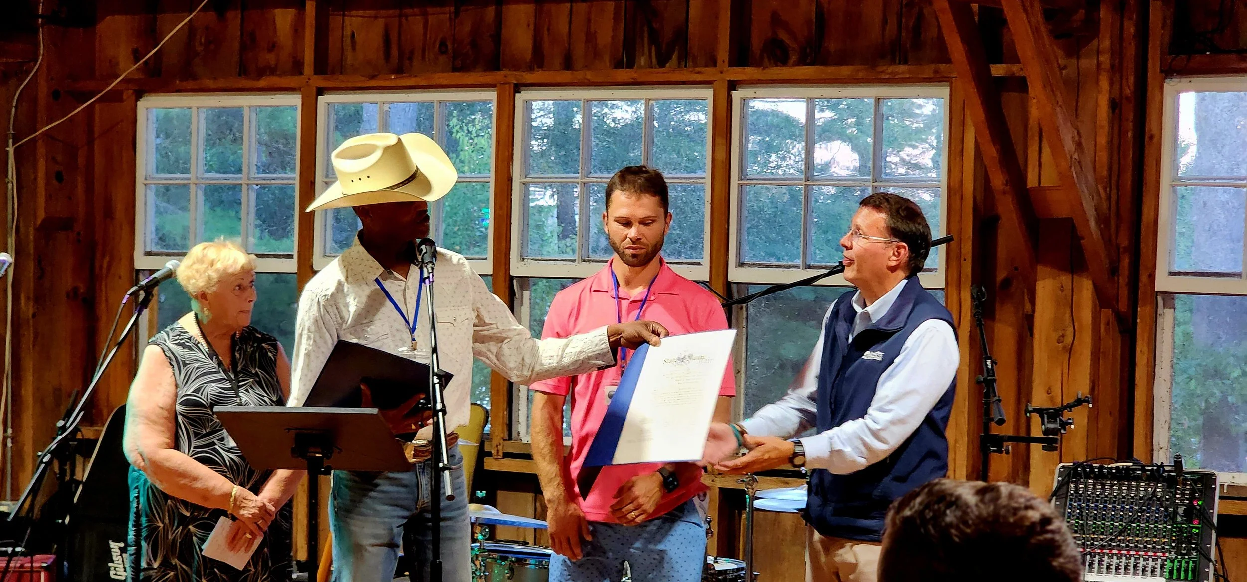 A woman and three men, the left most man is speaking into a microphone