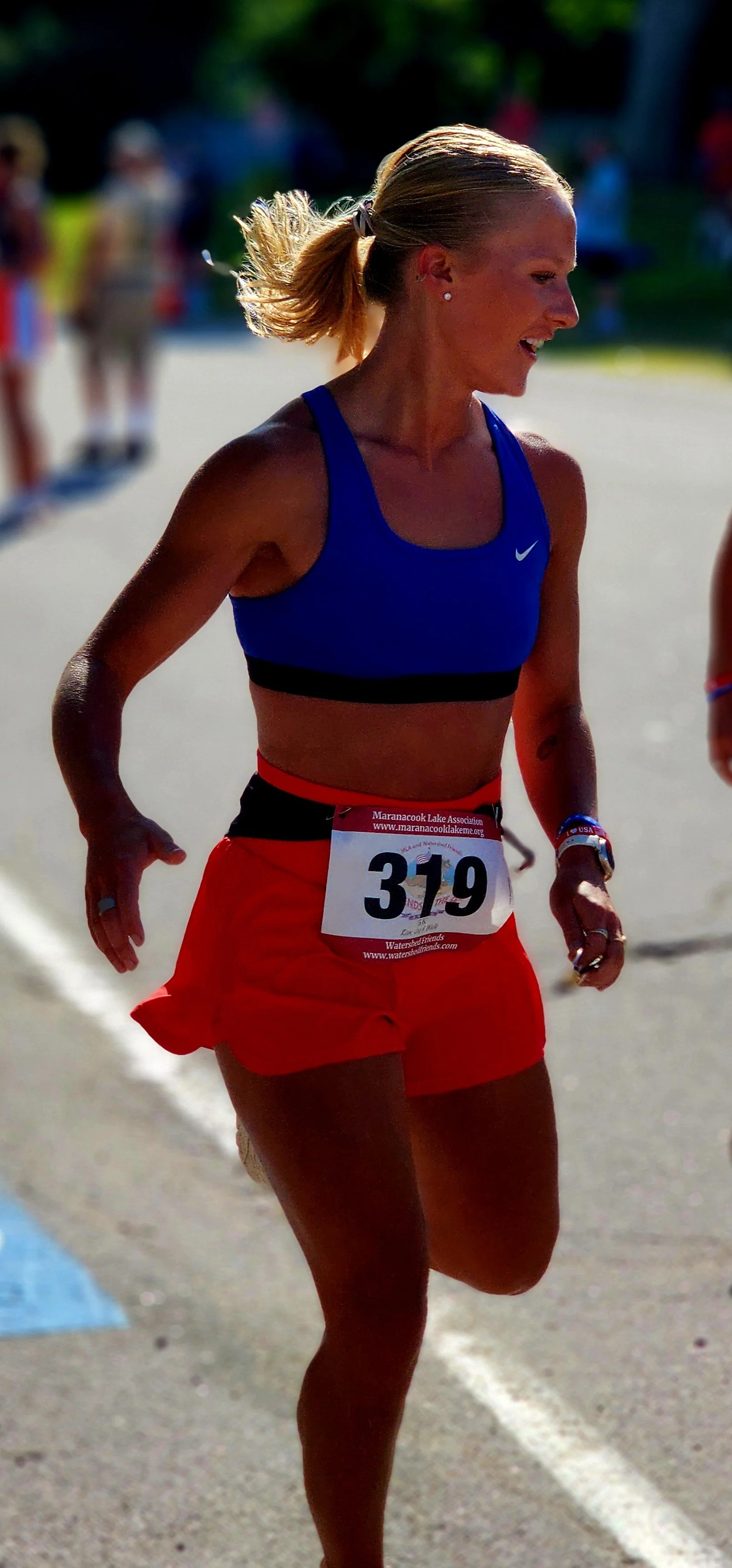 A woman wearing blue sports bra and red shorts running