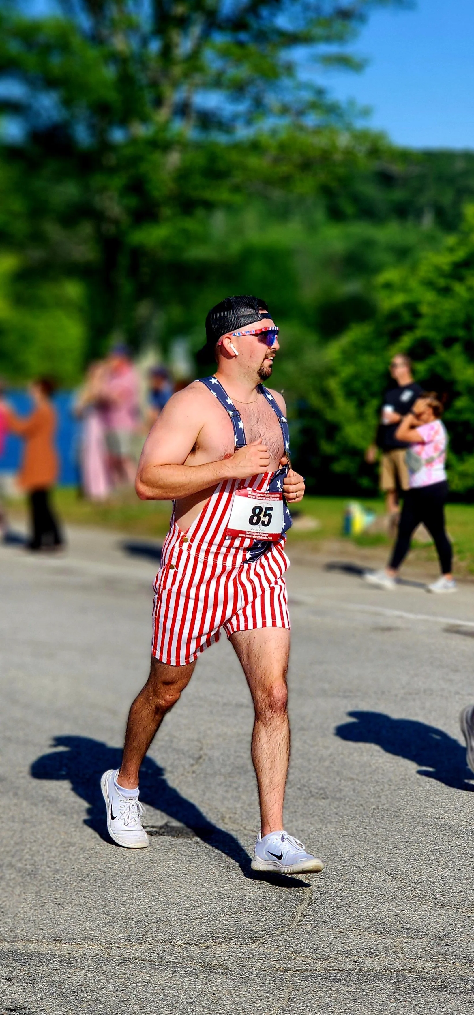 A man in a pair of American flag patterned overall shorts running 