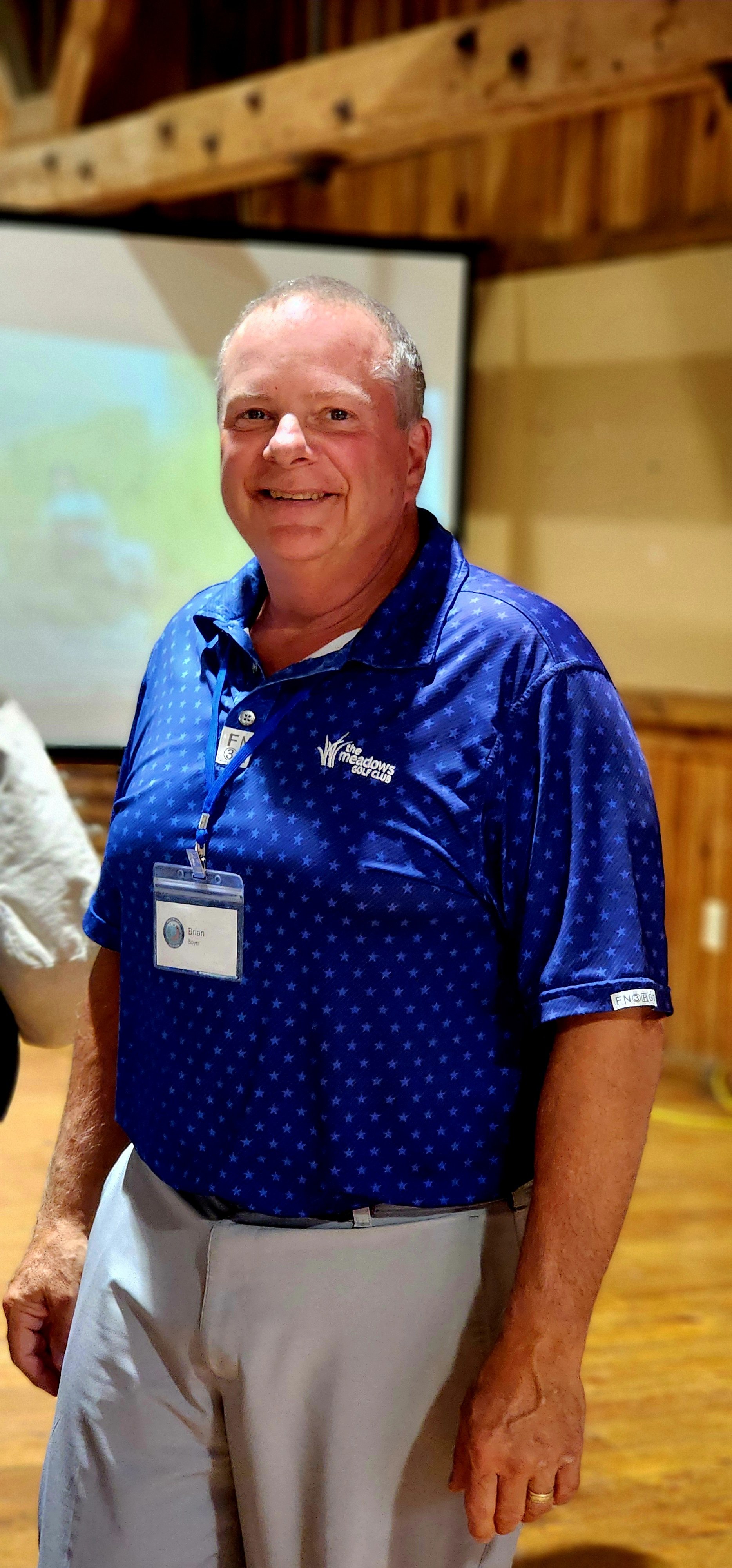 A man, wearing a blue polo and khakis, smiling at the camera