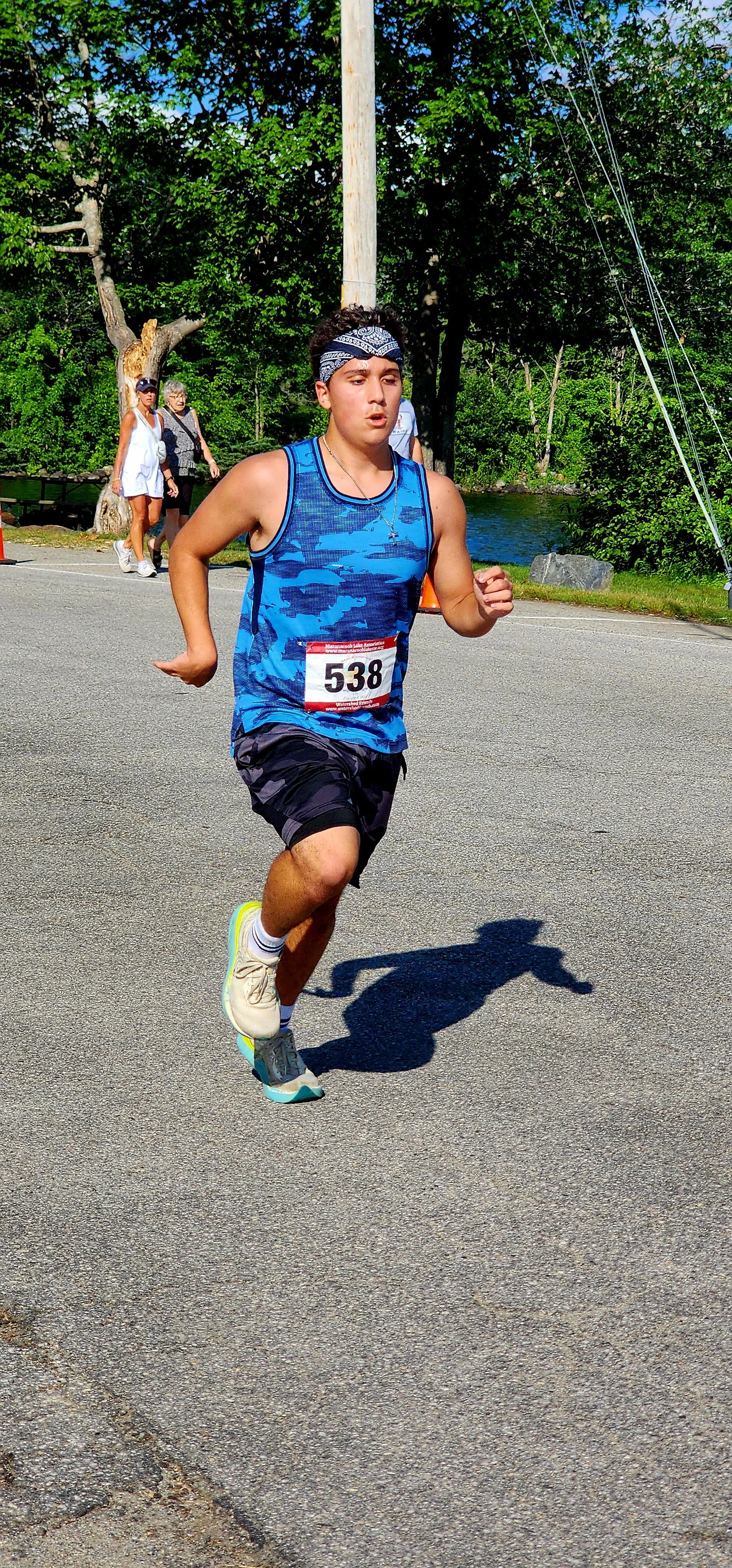 A person wearing a blue camo patterned tank top and dark grey camo patterned shorts running